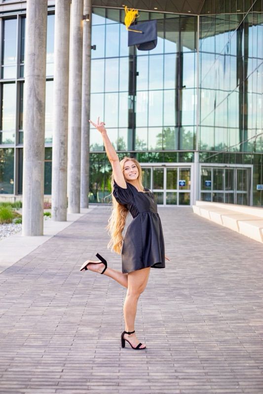 Person in black dress dances and twirls between modern architectural columns.