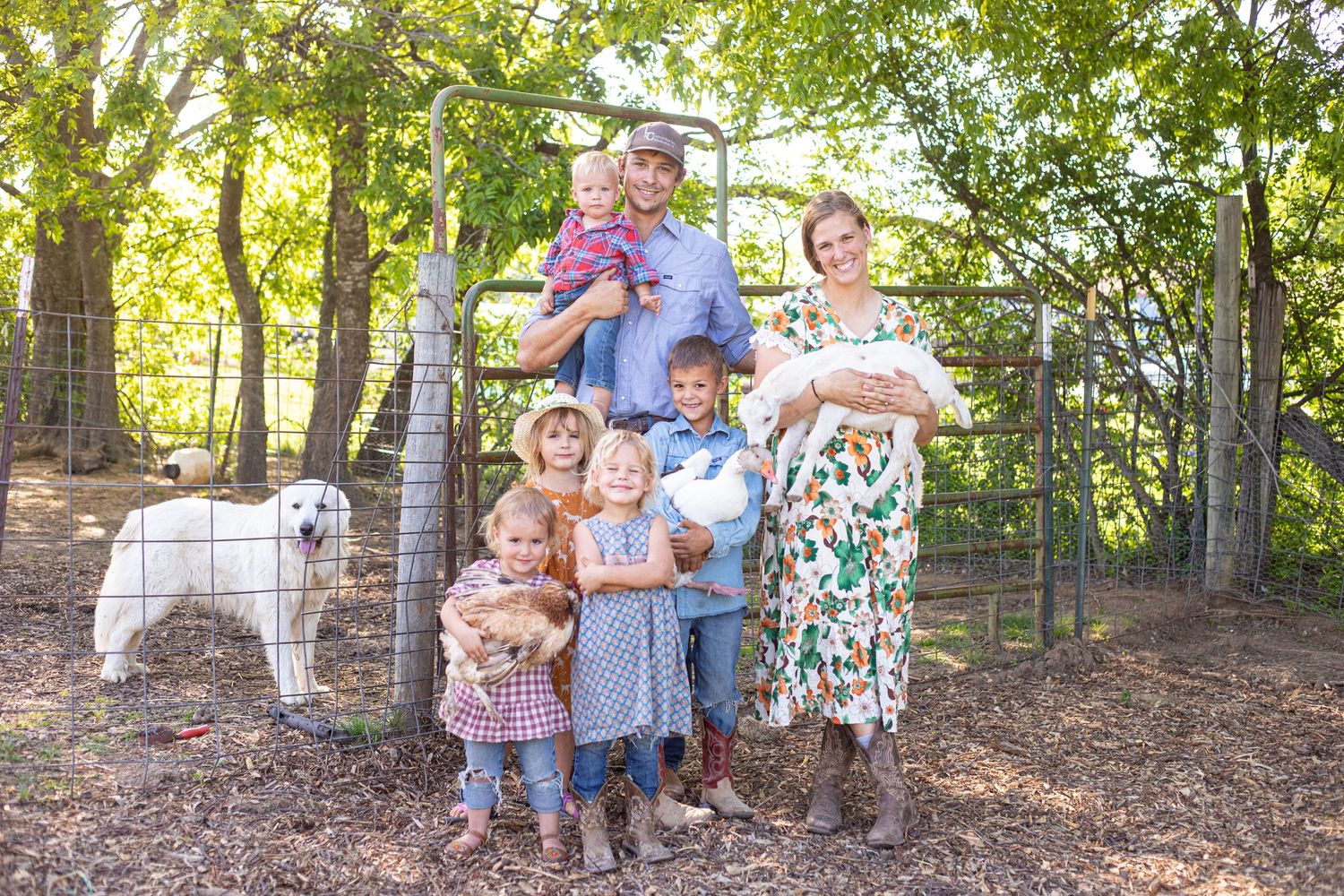 Family group photo taken outdoors with trees and natural lighting in background.