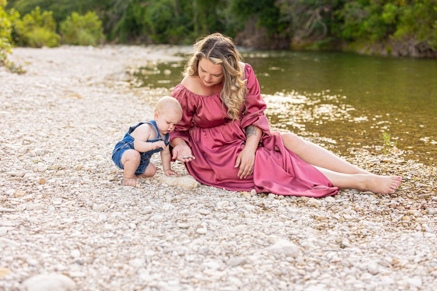 Family enjoying a peaceful afternoon by the rocky riverbank in coordinating pink outfits.