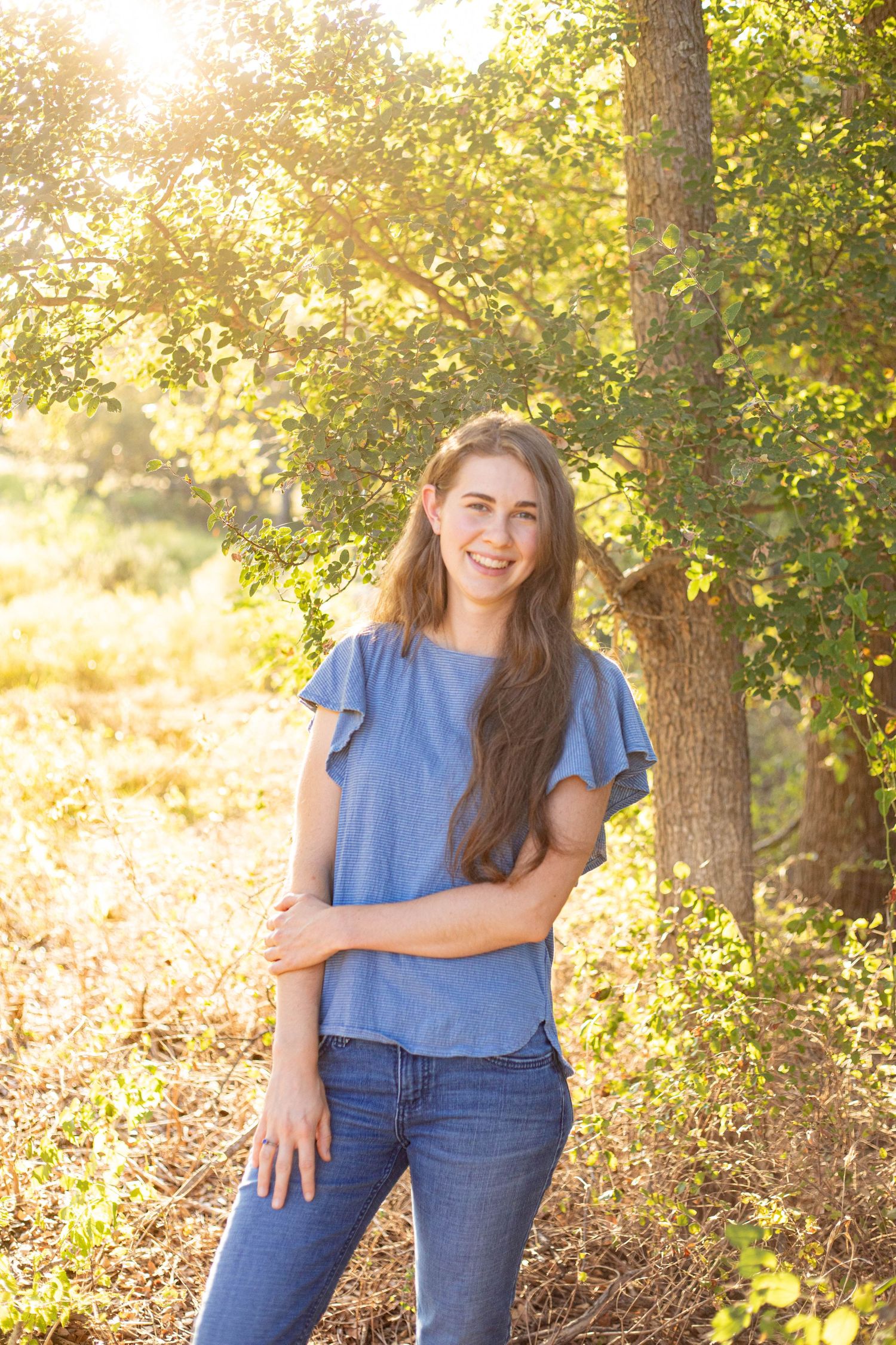 Casual denim outfit portrait with natural golden hour lighting in wooded setting.