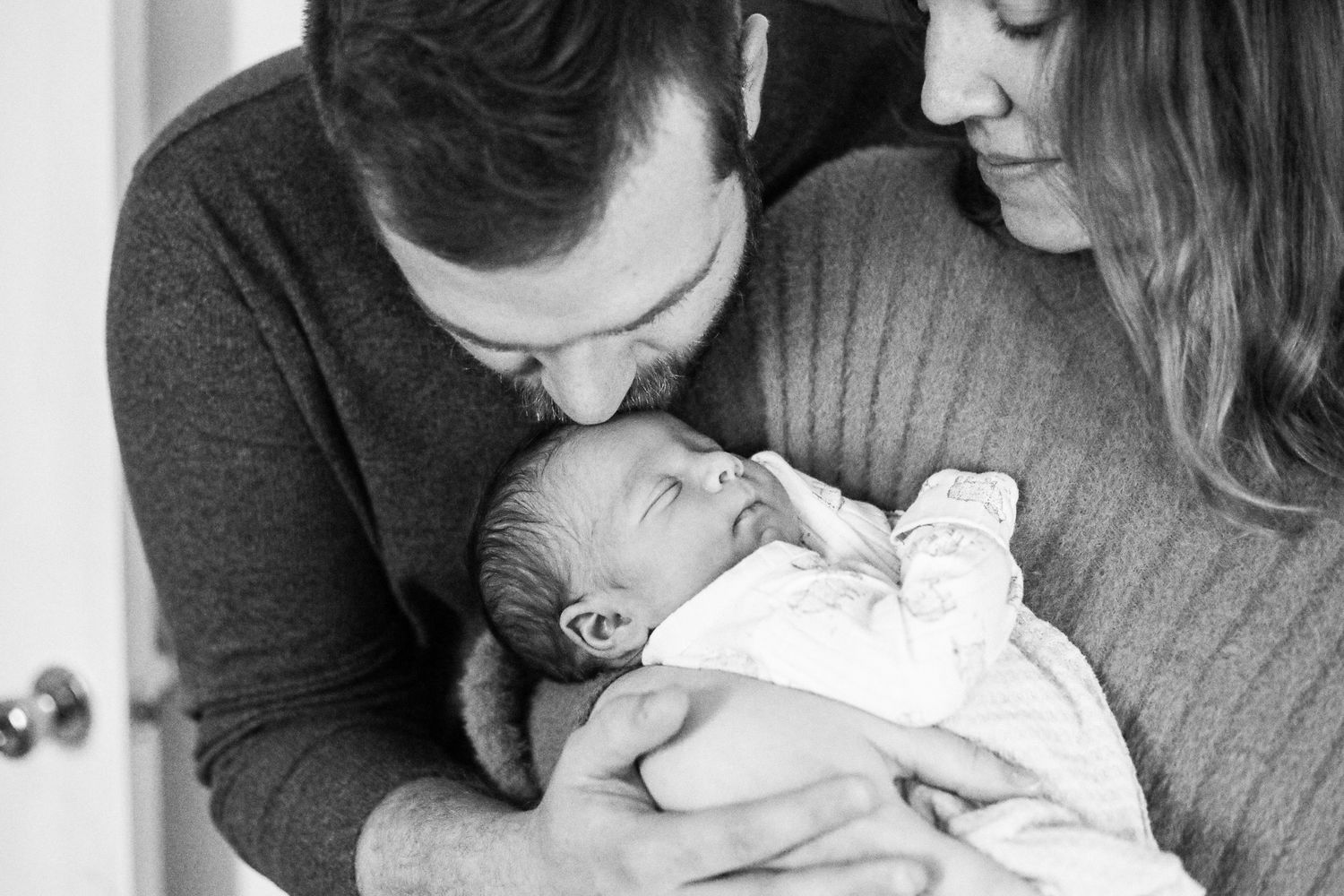 Intimate black and white portraits showing tender moments with a newborn.