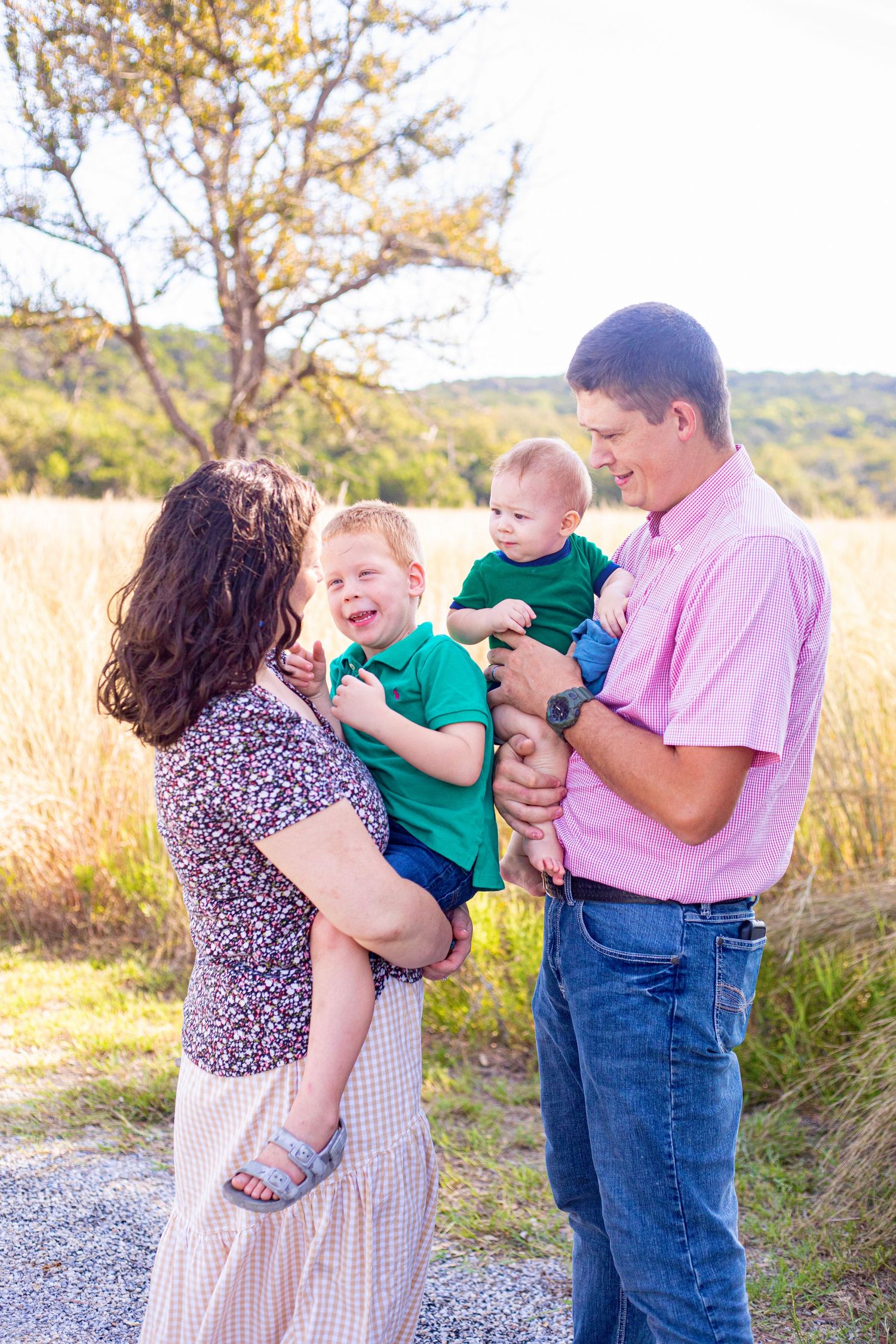 Family shares playful moments together in field during golden hour photoshoot.