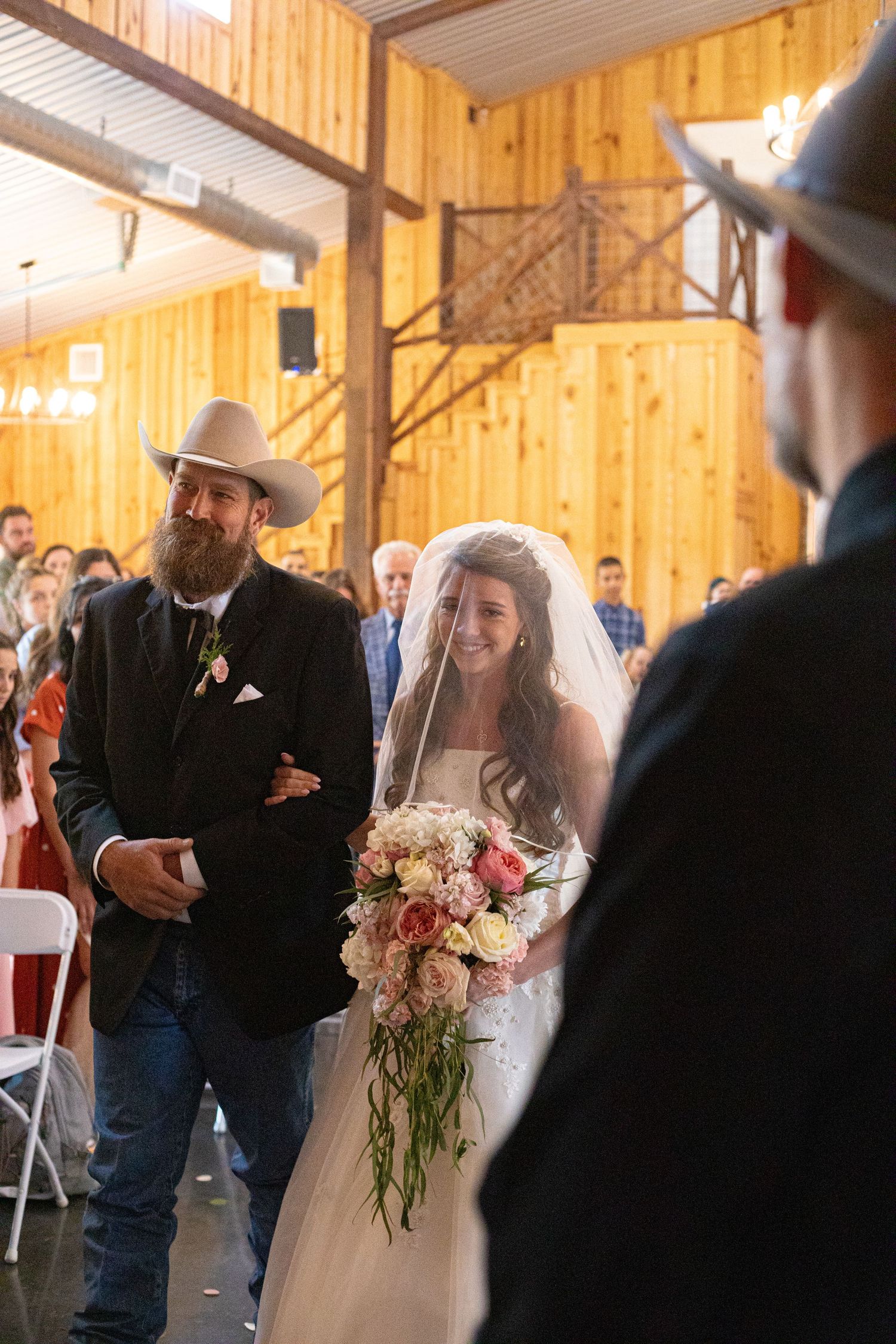 Wedding ceremony candid in rustic wooden barn with natural lighting.