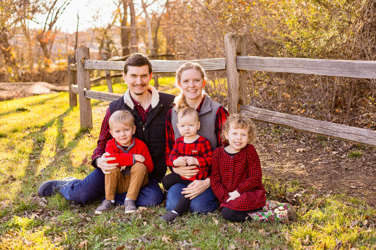 Autumn family portrait session along a rustic wooden fence.