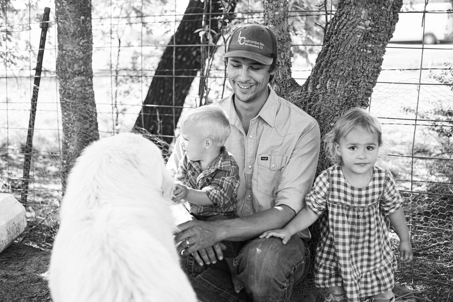 Black and white photo of family members interacting with farm animals.