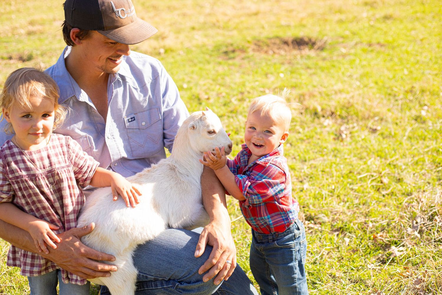Family enjoying a sunny day outdoors with a fluffy white dog.