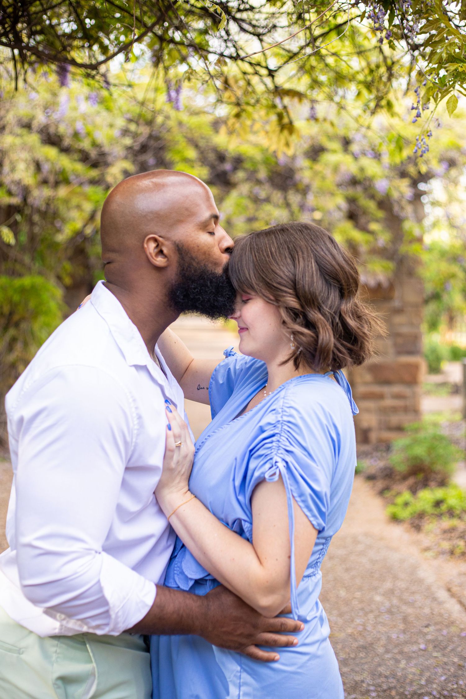An intimate moment between a couple on a garden path with lush greenery in the background.