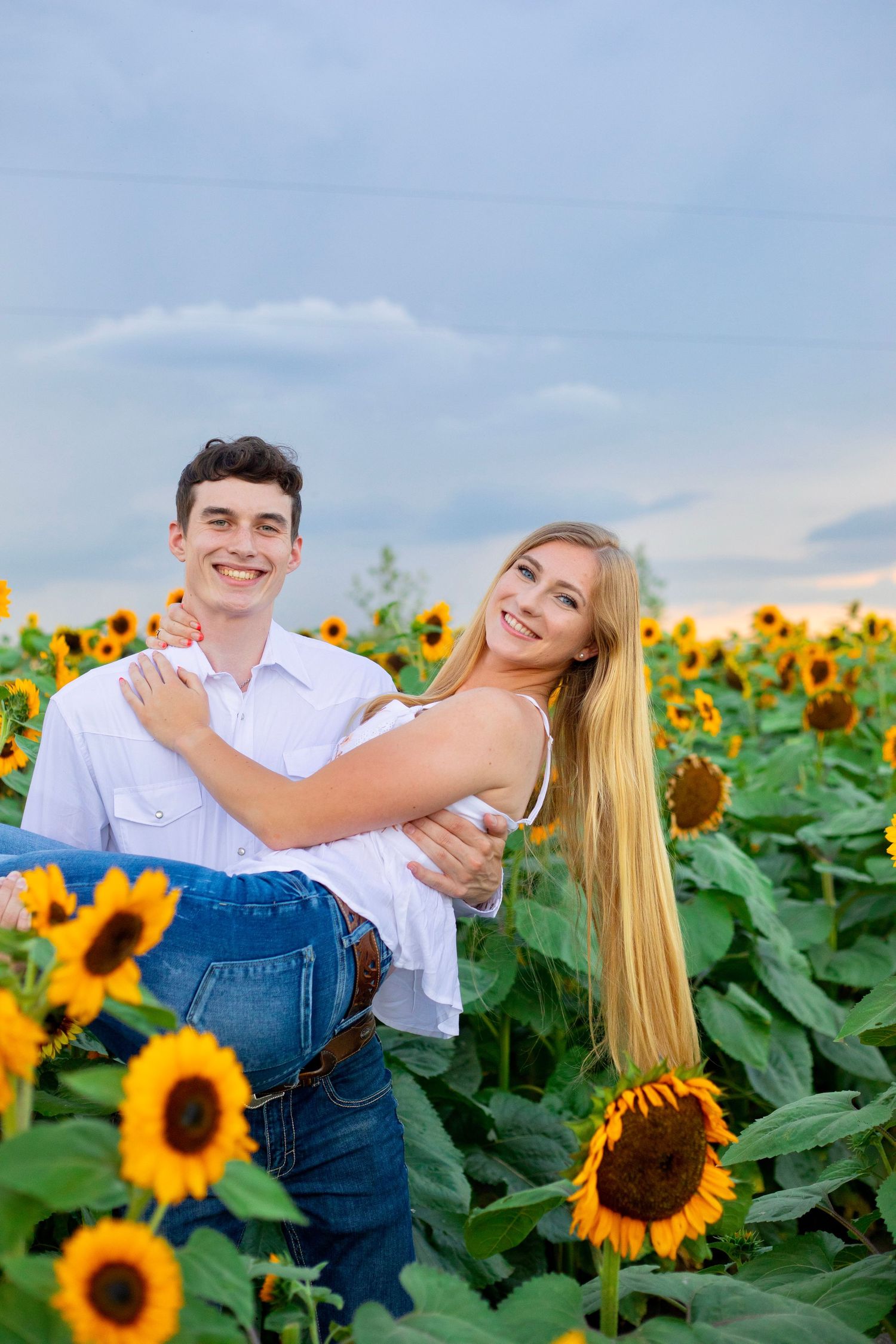 Happy couple shares playful moment among blooming sunflowers.