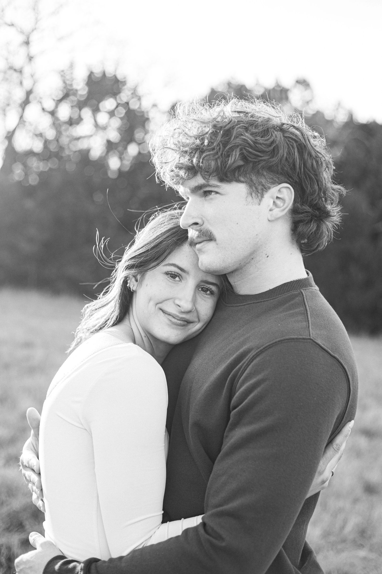 Black and white portrait of couple sharing a tender embrace outdoors.