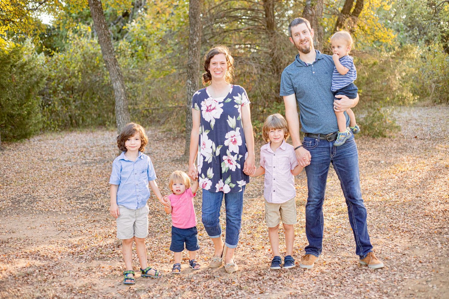 Family walking together through a scenic autumn forest with golden leaves.