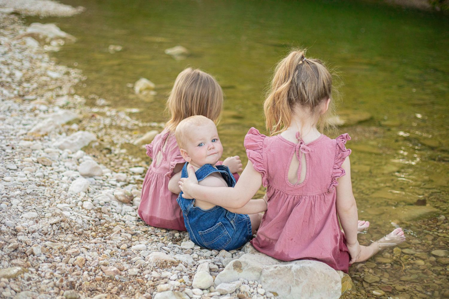 Group relaxes on rocky riverbank wearing coordinated pink and blue outfits.