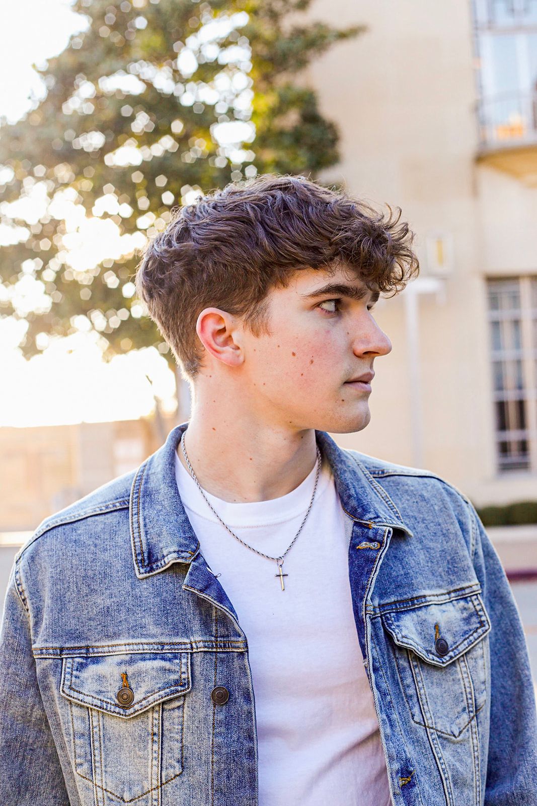 Stylish denim jacket poses against a sunlit architectural backdrop.