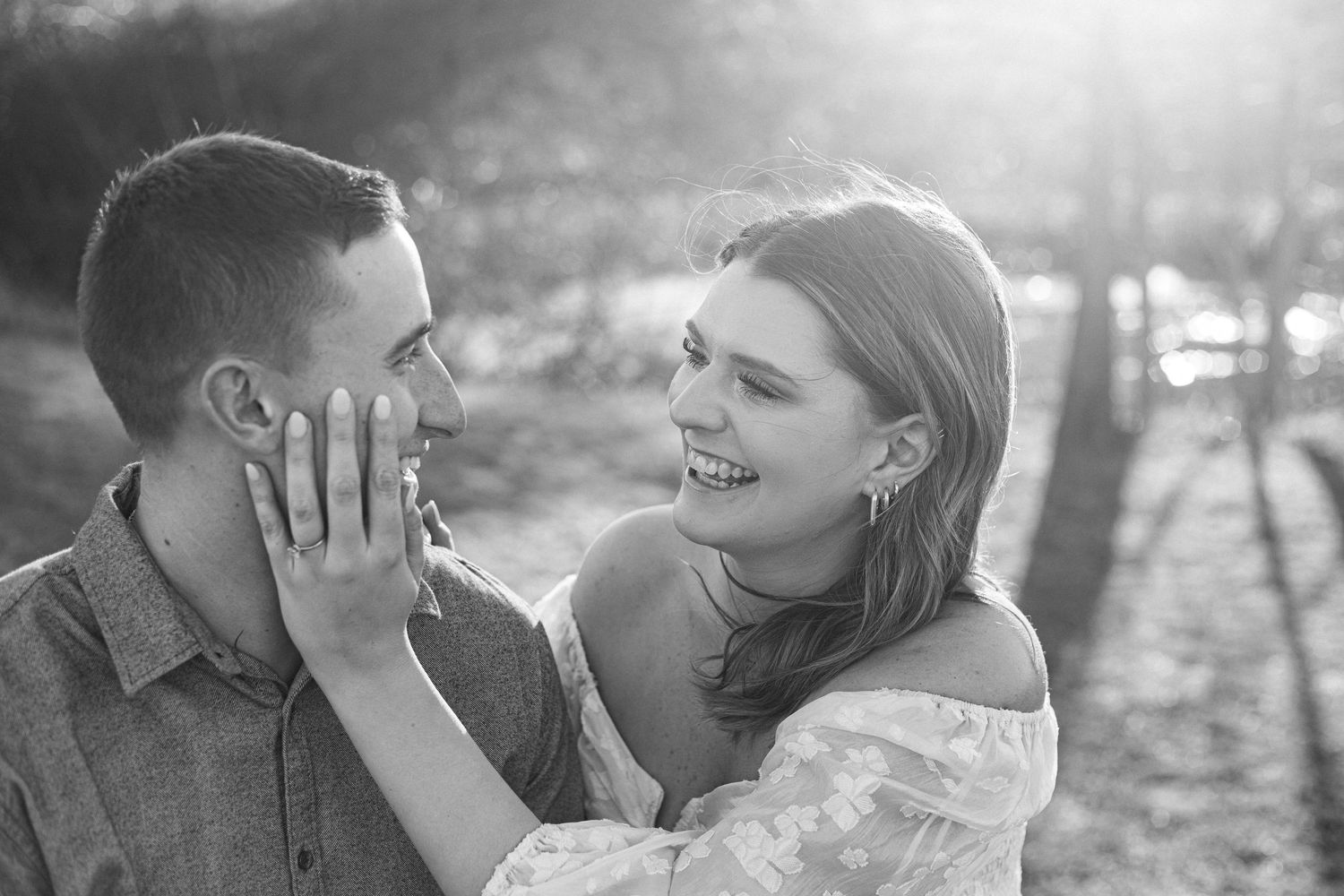 A romantic black and white portrait of a couple sharing a tender moment in natural lighting.