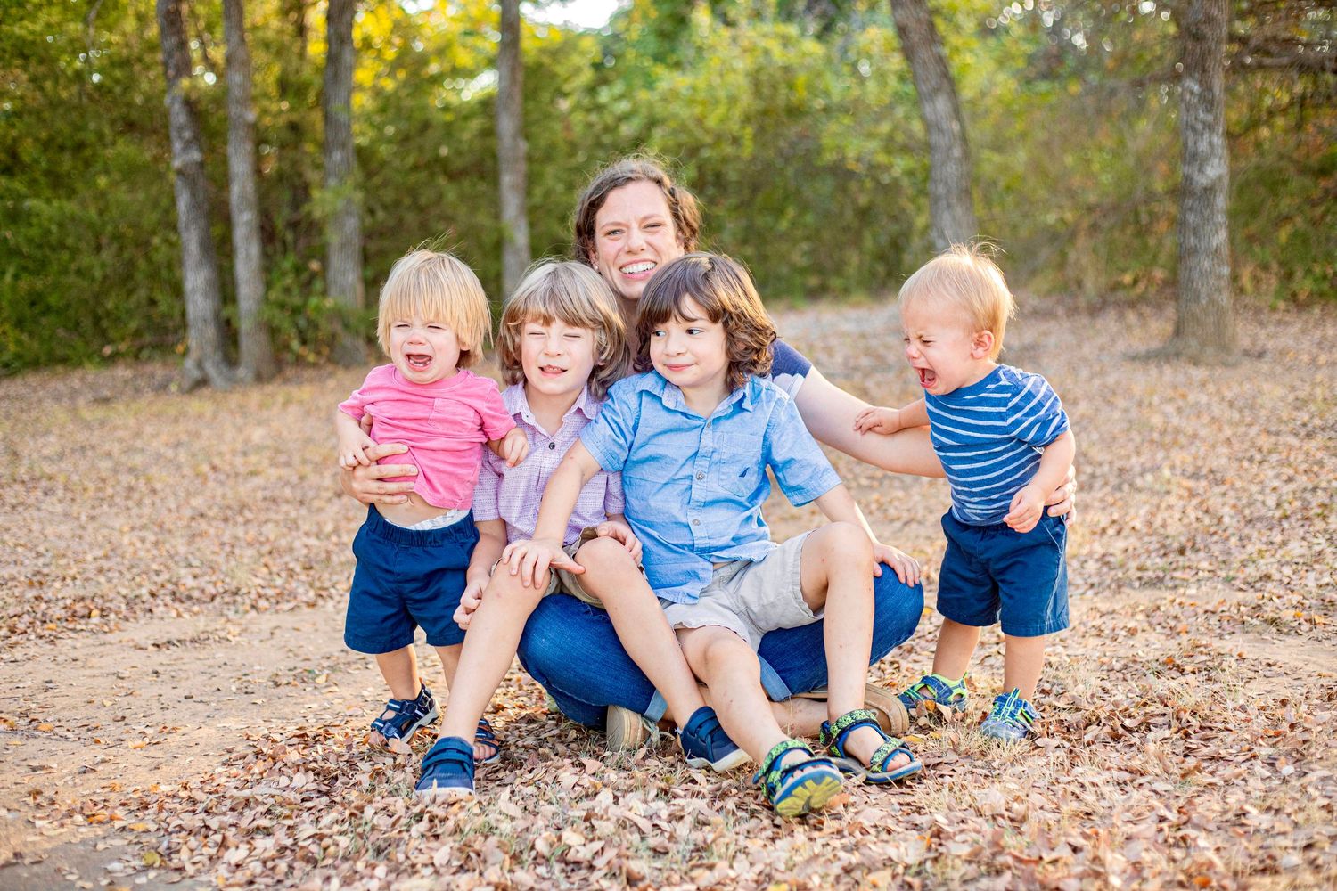 Group relaxing on fallen leaves in a wooded area during golden hour.