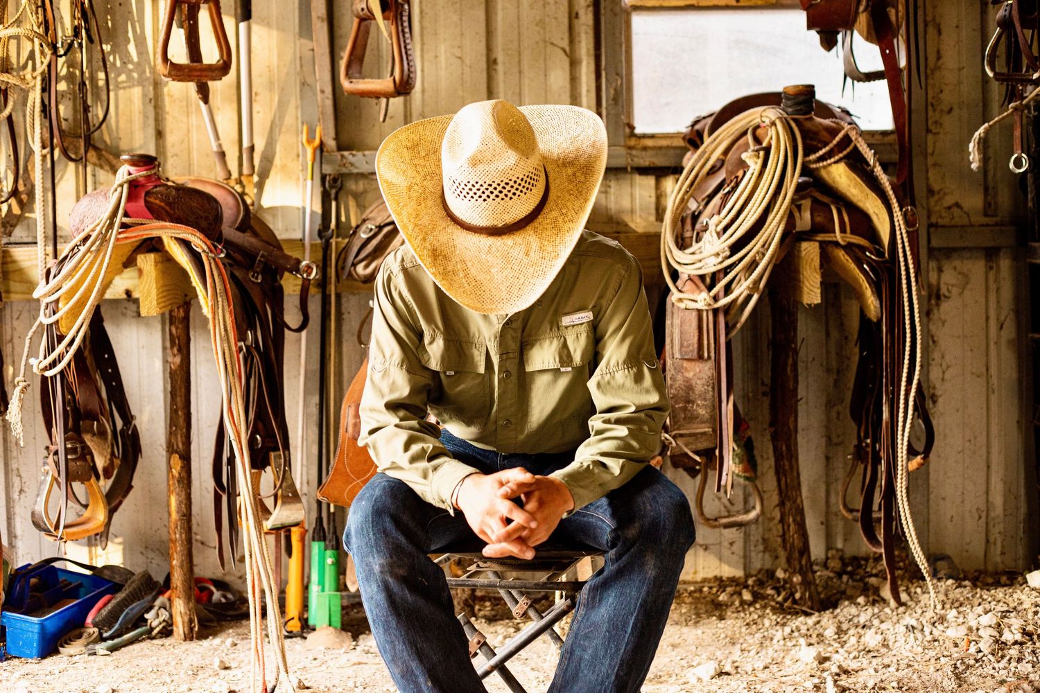 Interior of a rustic barn with saddles, ropes and western equipment on display.