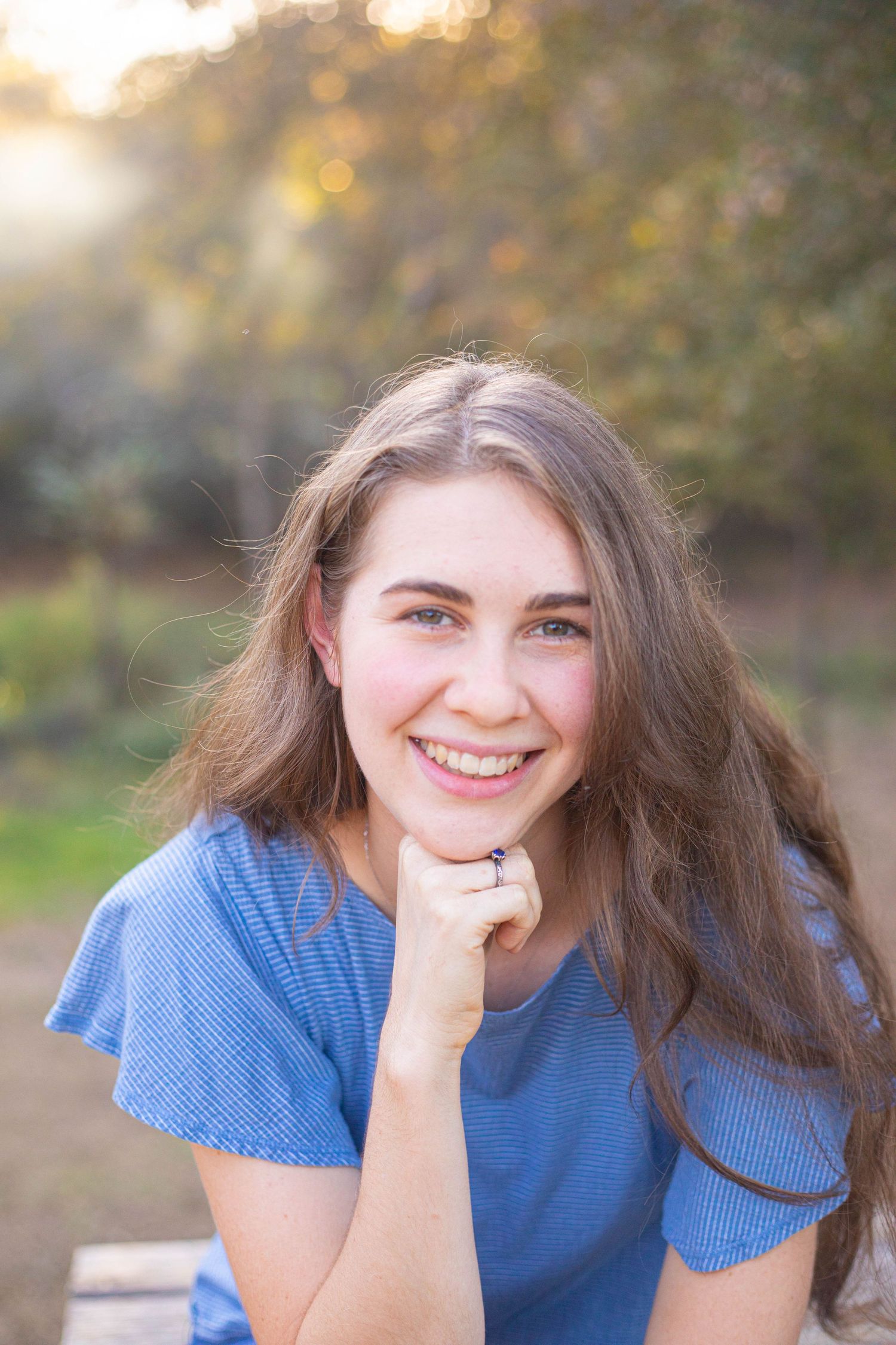 Portrait shot with warm sunset lighting and natural outdoor backdrop.