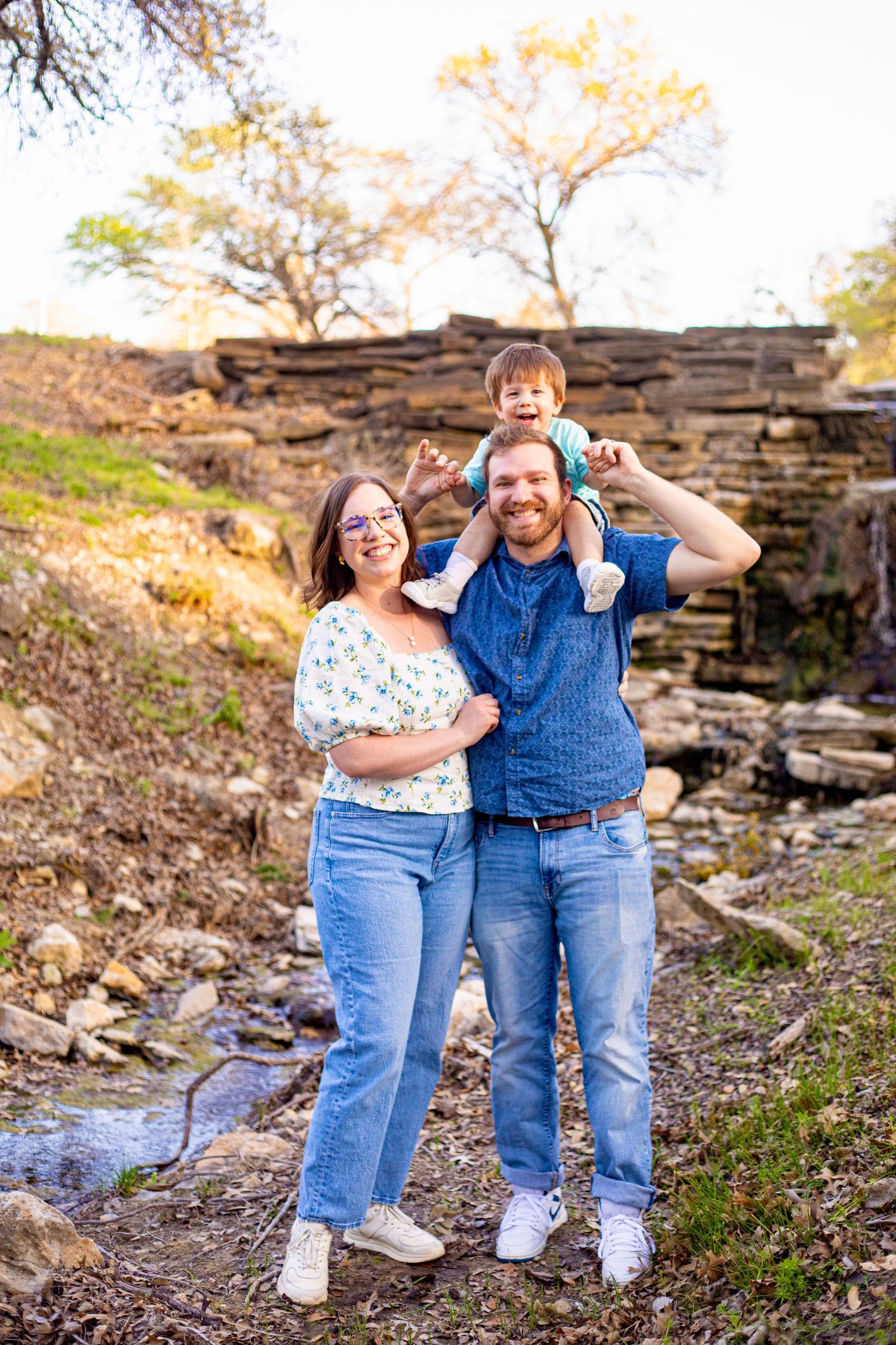 Casual family photoshoot on rocky terrain showing playful interactions.