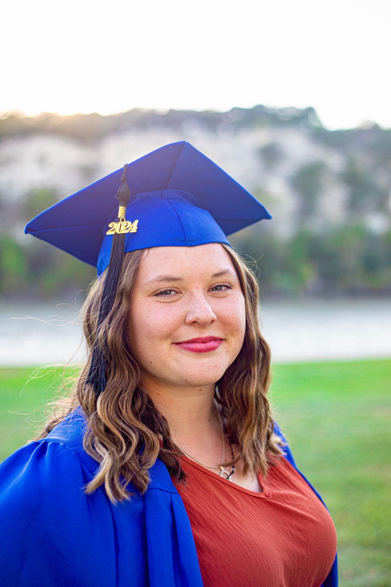A graduation portrait featuring a 2024 graduate in traditional blue cap and gown.