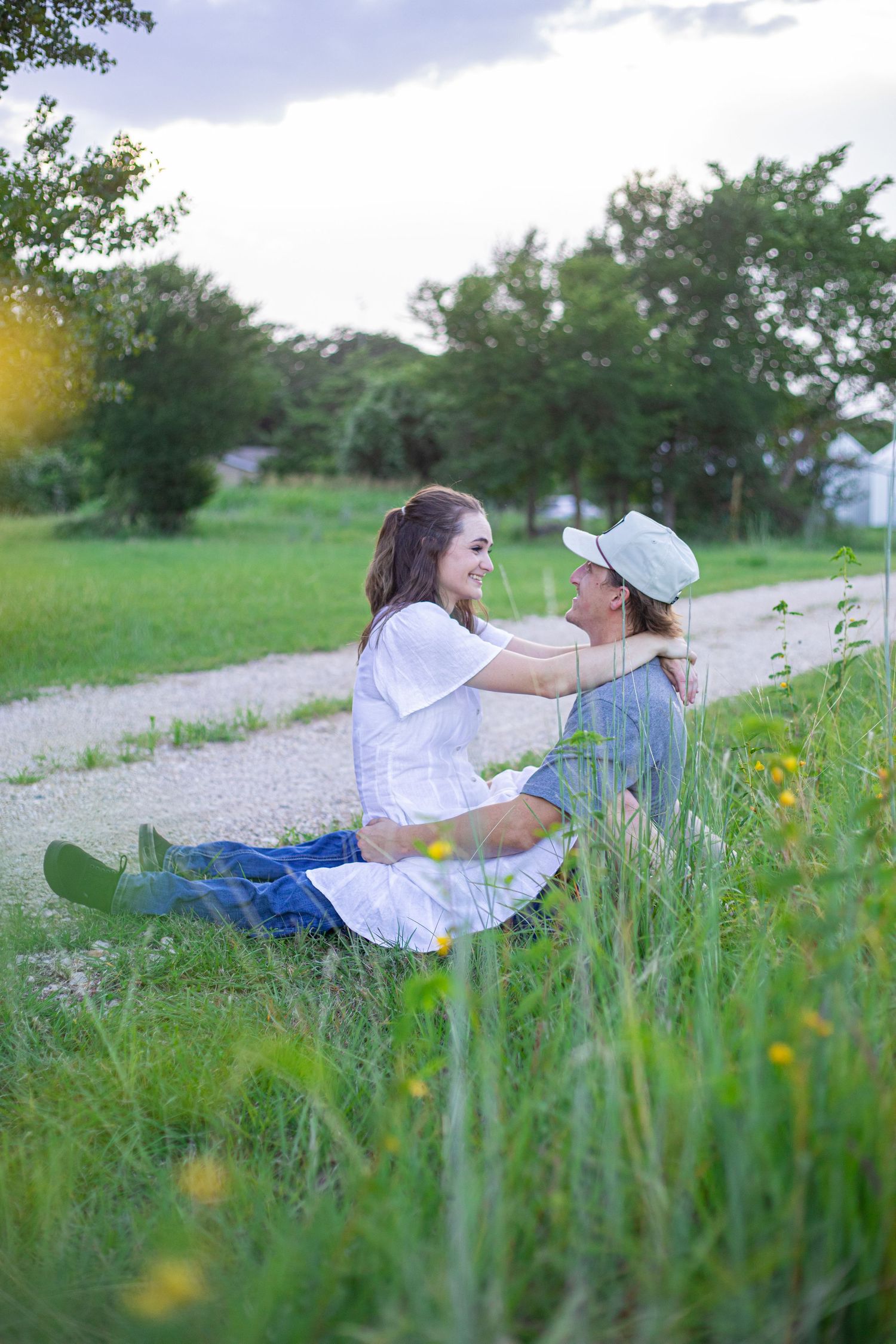 A couple reclines in tall grass during a romantic outdoor photoshoot.