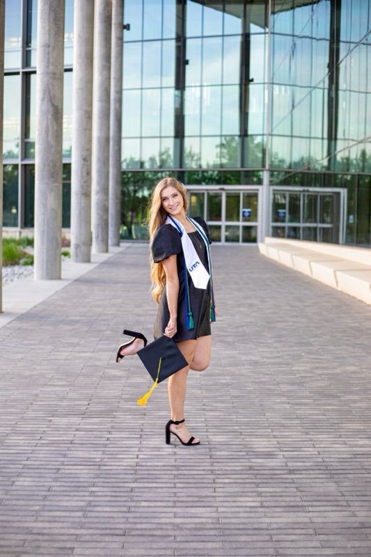 Graduate photoshoot on campus featuring modern architectural elements and columns.