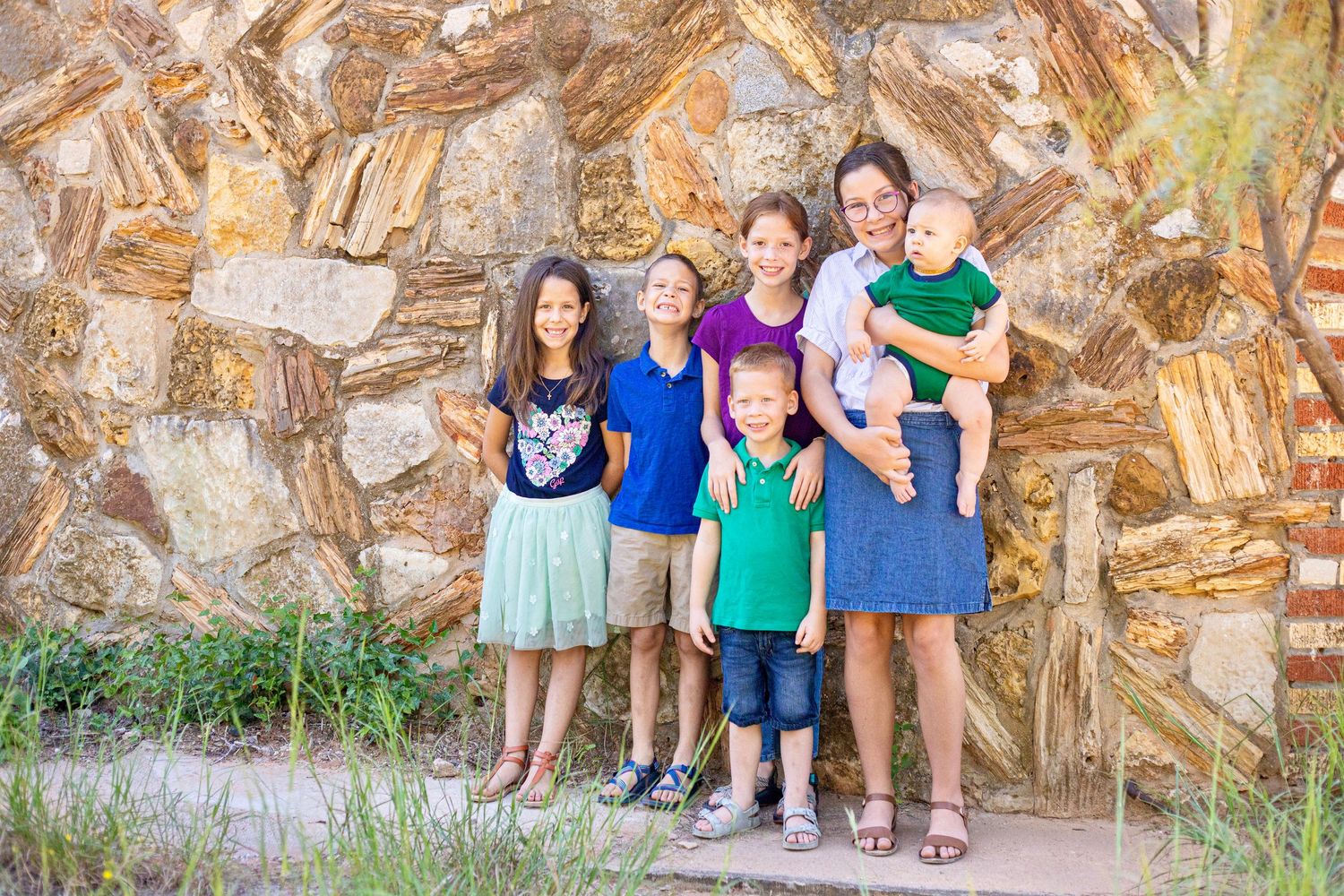 Group photo against textured stone wall with natural outdoor lighting.