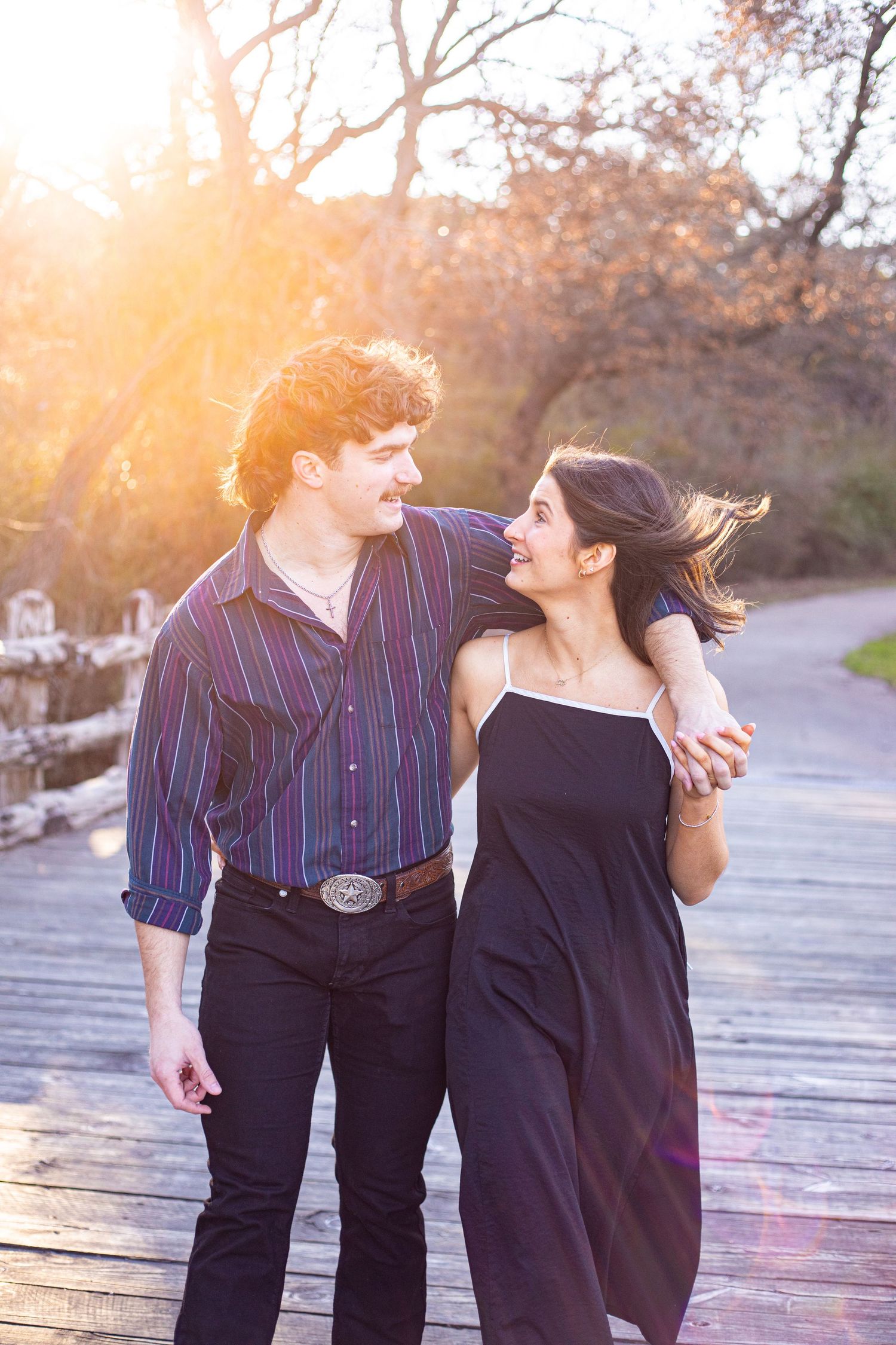 Romantic couple sharing a tender moment while dancing on a wooden deck at golden hour.