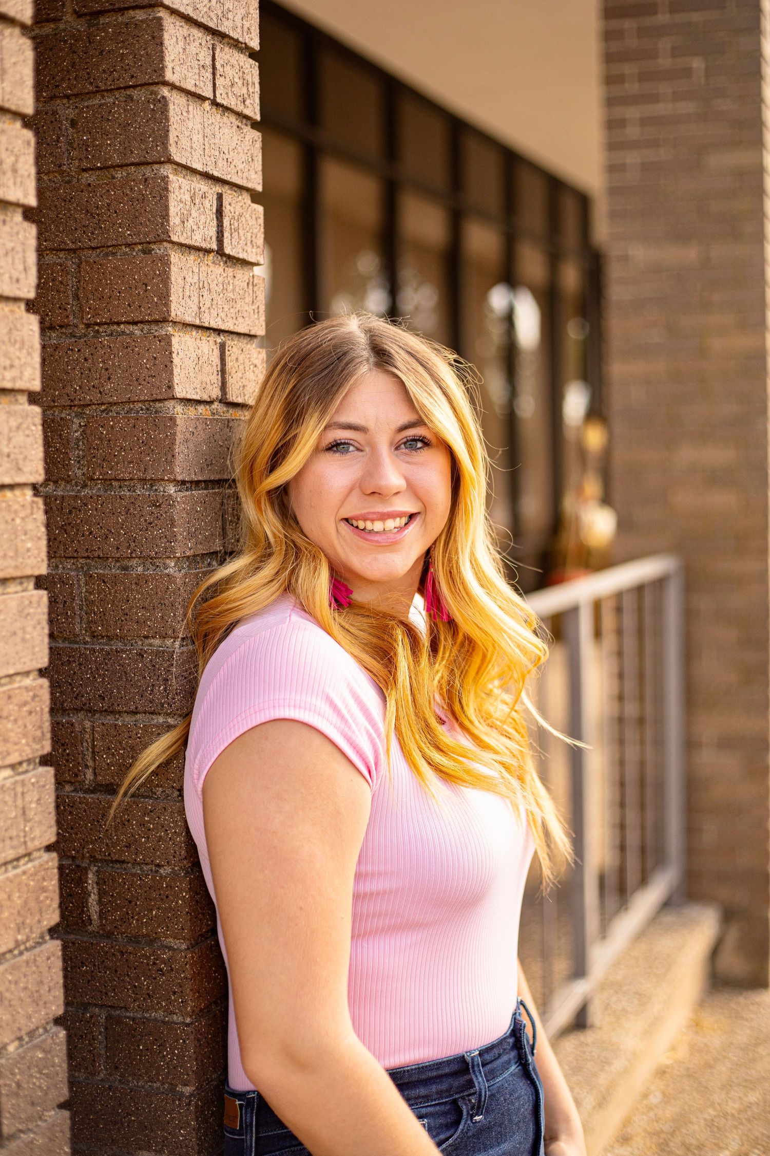 Portrait series featuring pink top against brick column backdrop.