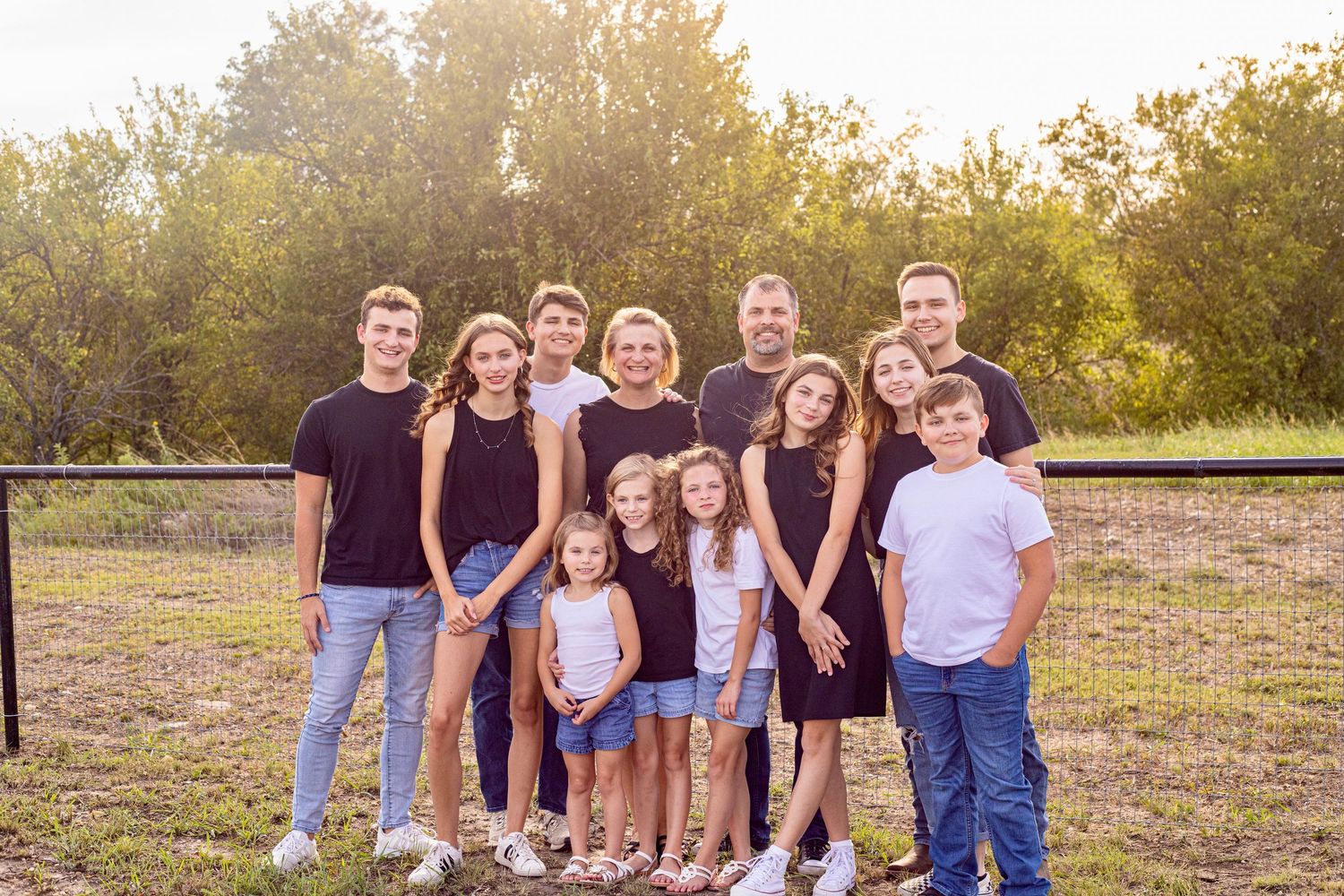 Extended family gathering photographed in warm evening light on a grassy hillside.