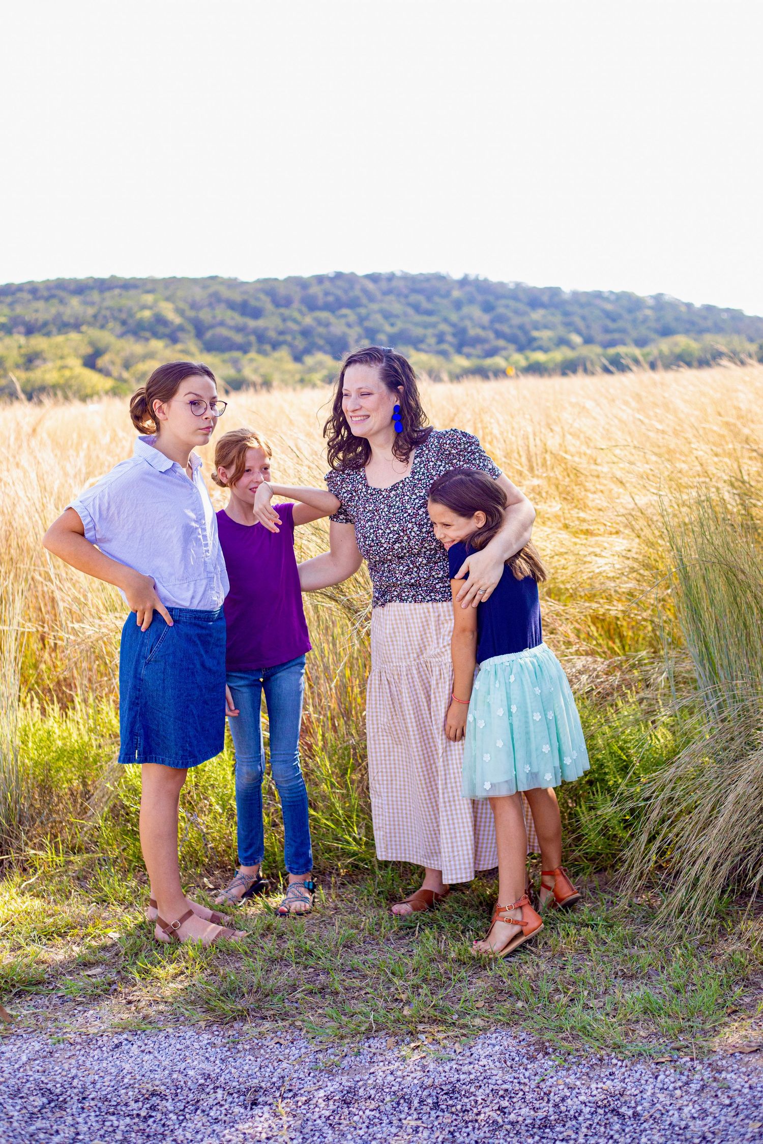 Candid group photo with everyone laughing together against a backdrop of golden grass.
