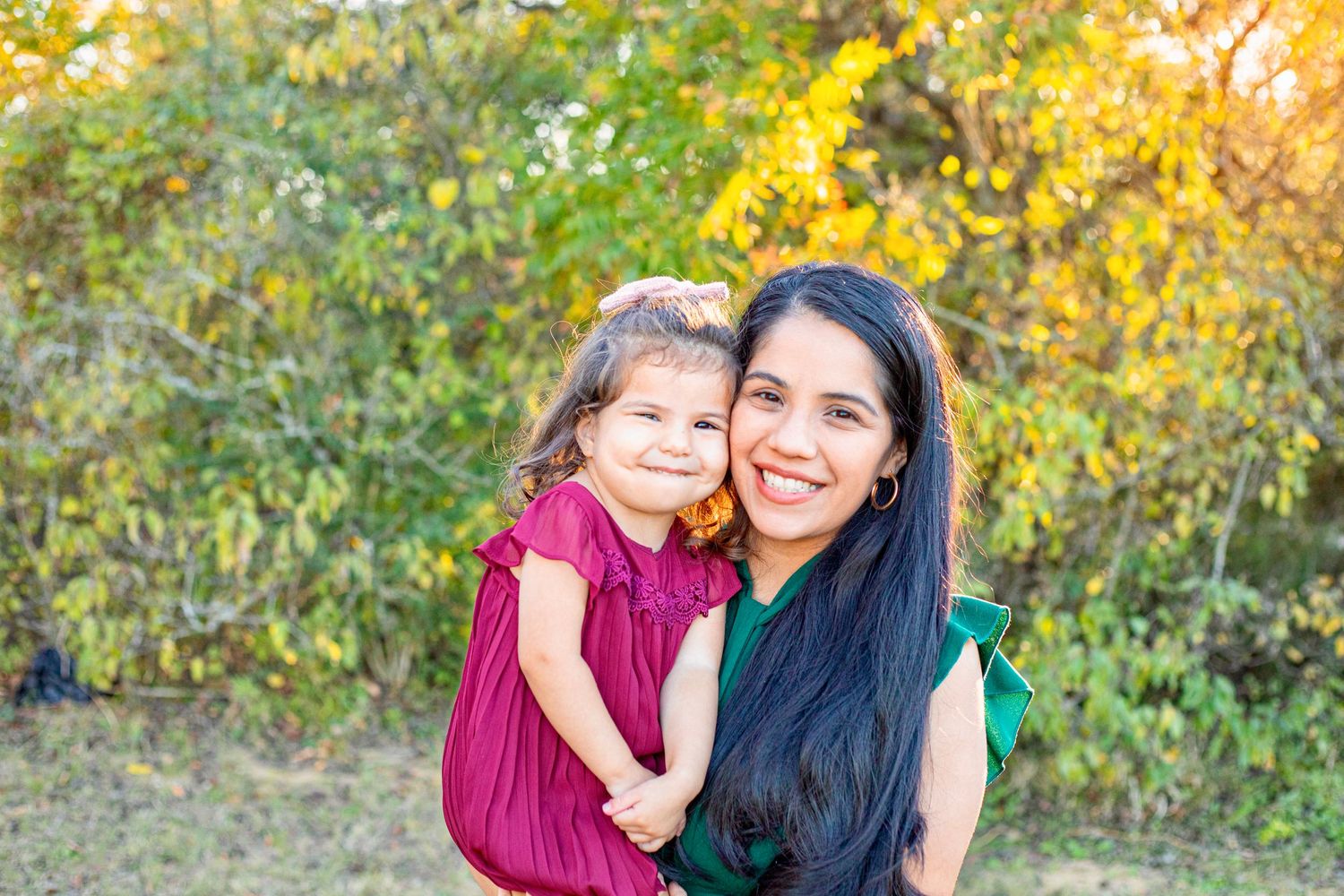 Family photos taken outdoors in autumn with burgundy clothing against golden foliage.