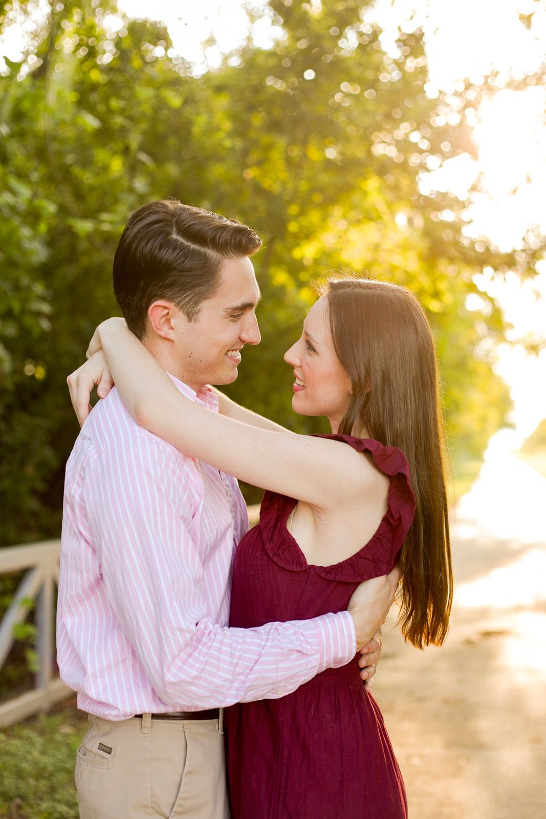Couple embraces on sunlit path during romantic sunset moment.
