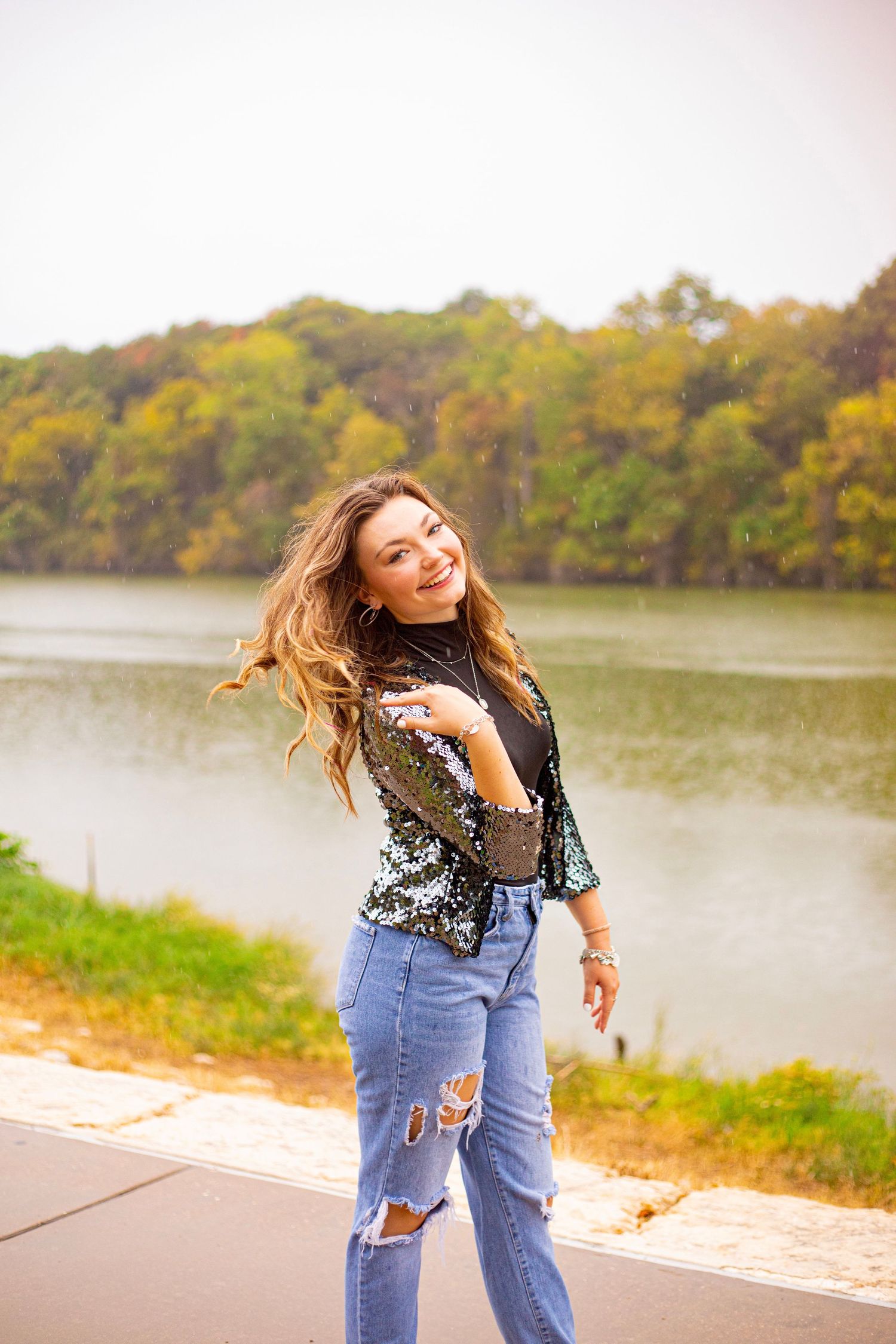 Energetic dance moves captured by the lake in denim and sequins during golden hour.