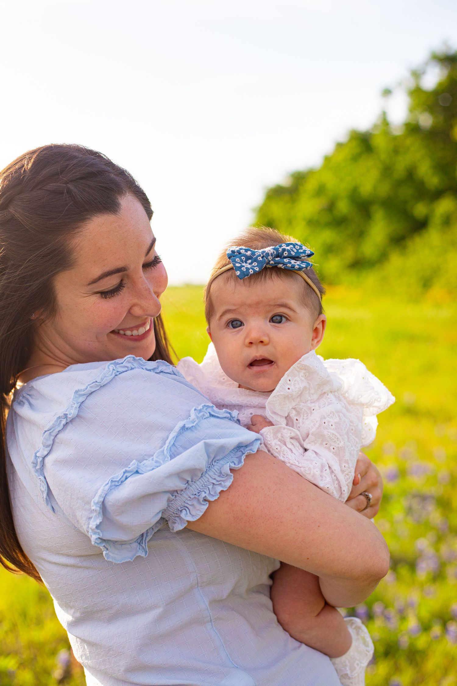 Mother and baby sharing tender moments in a wildflower field at sunset.