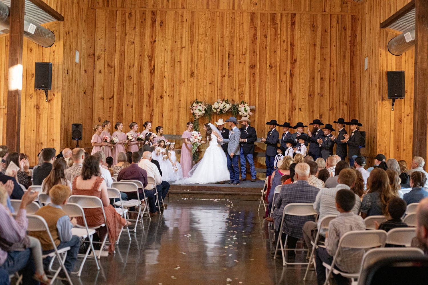 Large wooden barn interior set up for wedding reception with rows of tables and chairs.