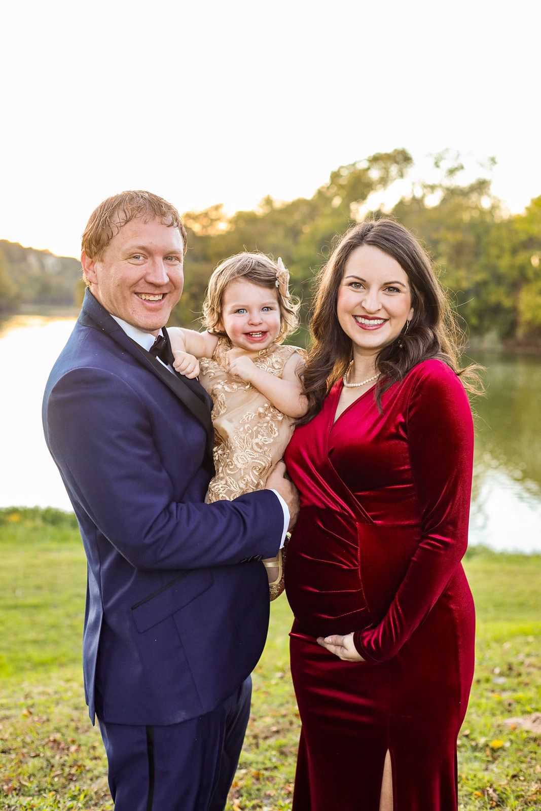 Family photos in a park setting with a burgundy velvet dress and navy suit at sunset.