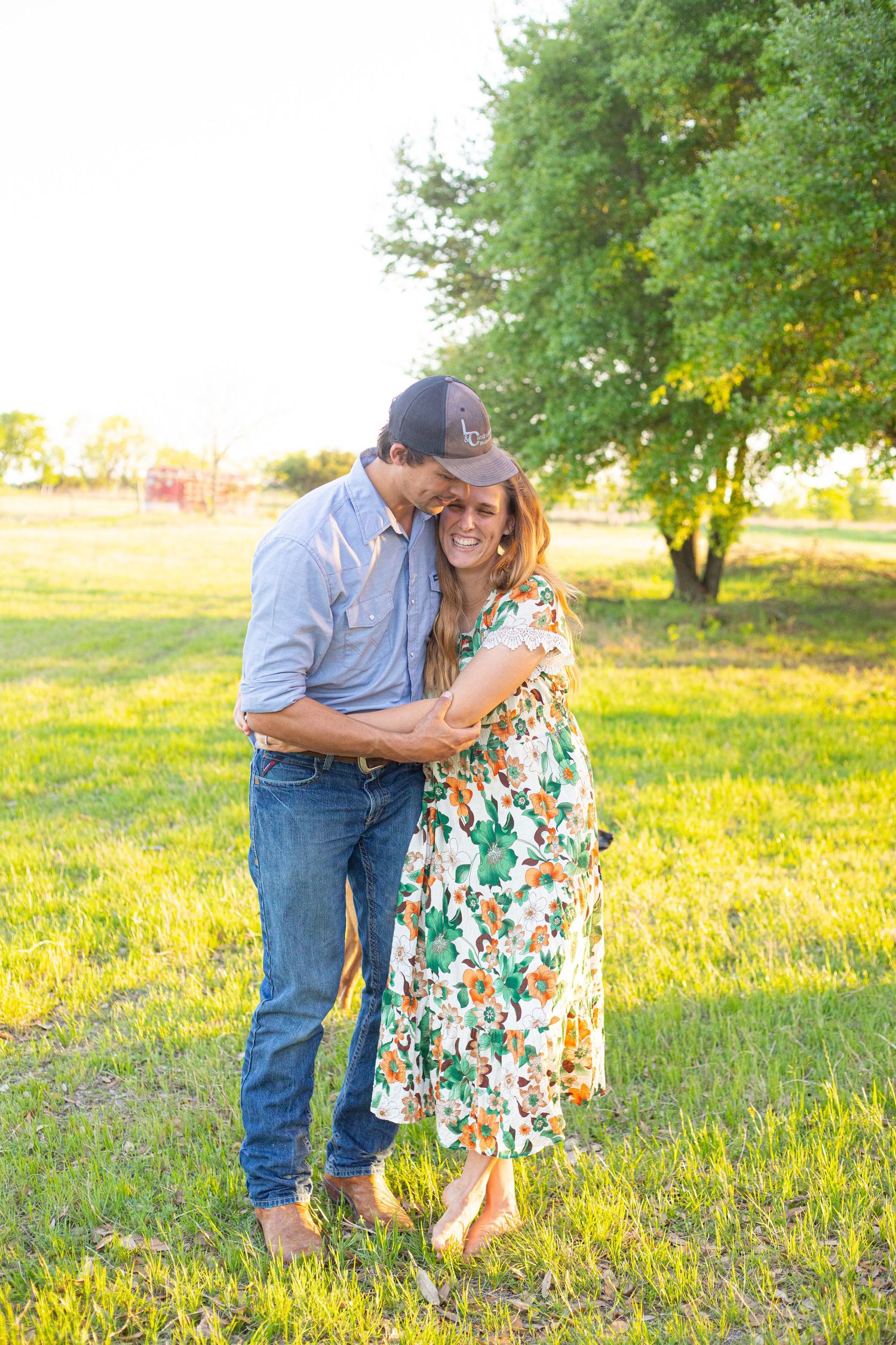 Couple sharing intimate moment in floral dress and denim in sunny field.