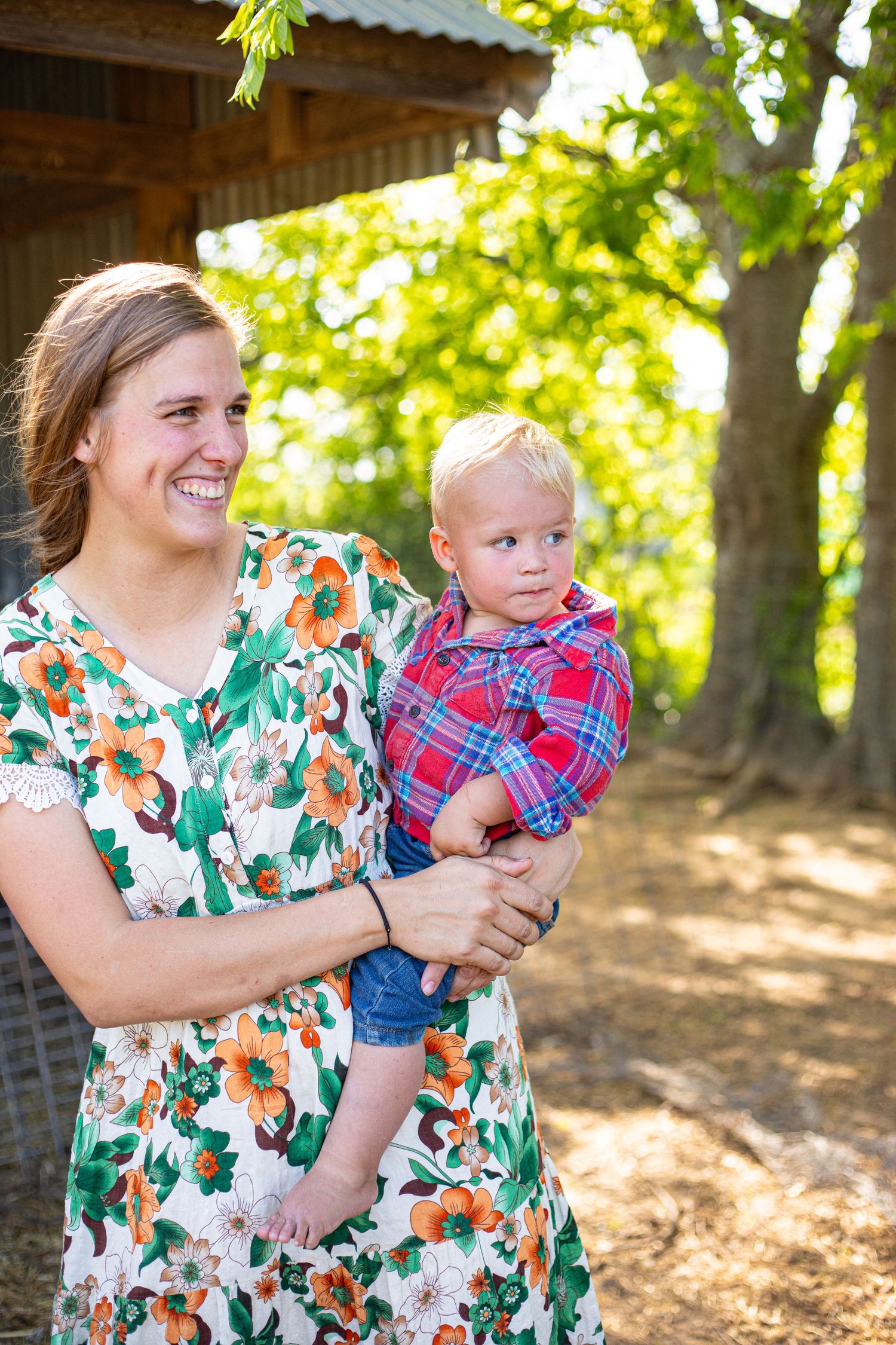 Family enjoying a sunny day outdoors near a rustic barn structure.