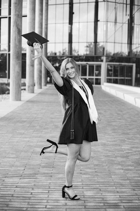 Black and white graduation photo with modern architectural backdrop and columns.
