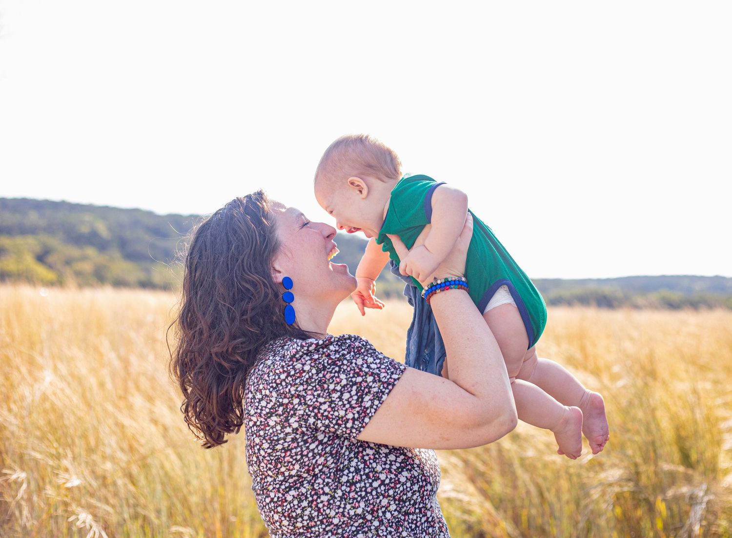 A family shares playful moments in a golden wheat field during sunset.