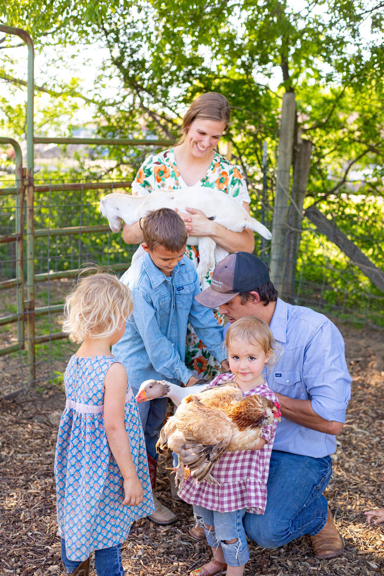 Family gathering outdoors with chickens and children in a natural wooded setting.