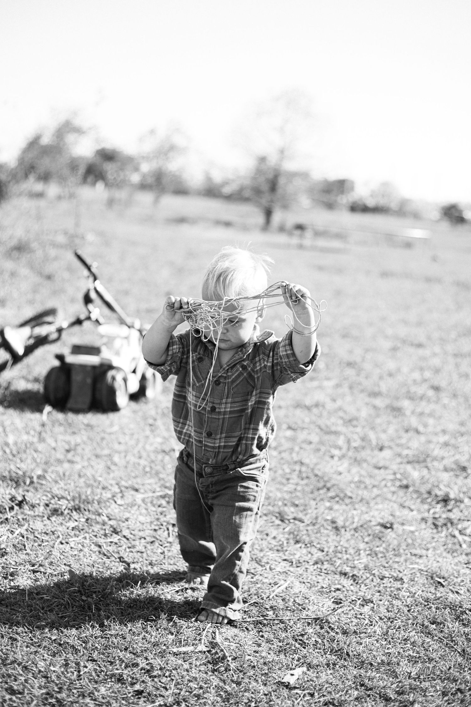 Black and white photo showing small figure crawling on grassy ground in natural lighting.