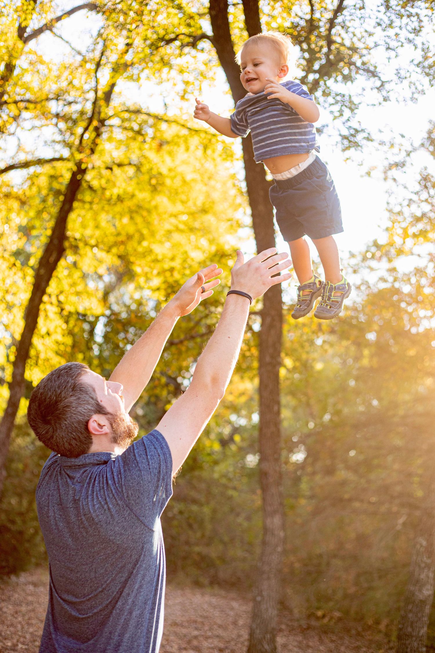 A playful scene of lifting and swinging in a sunlit autumn forest.