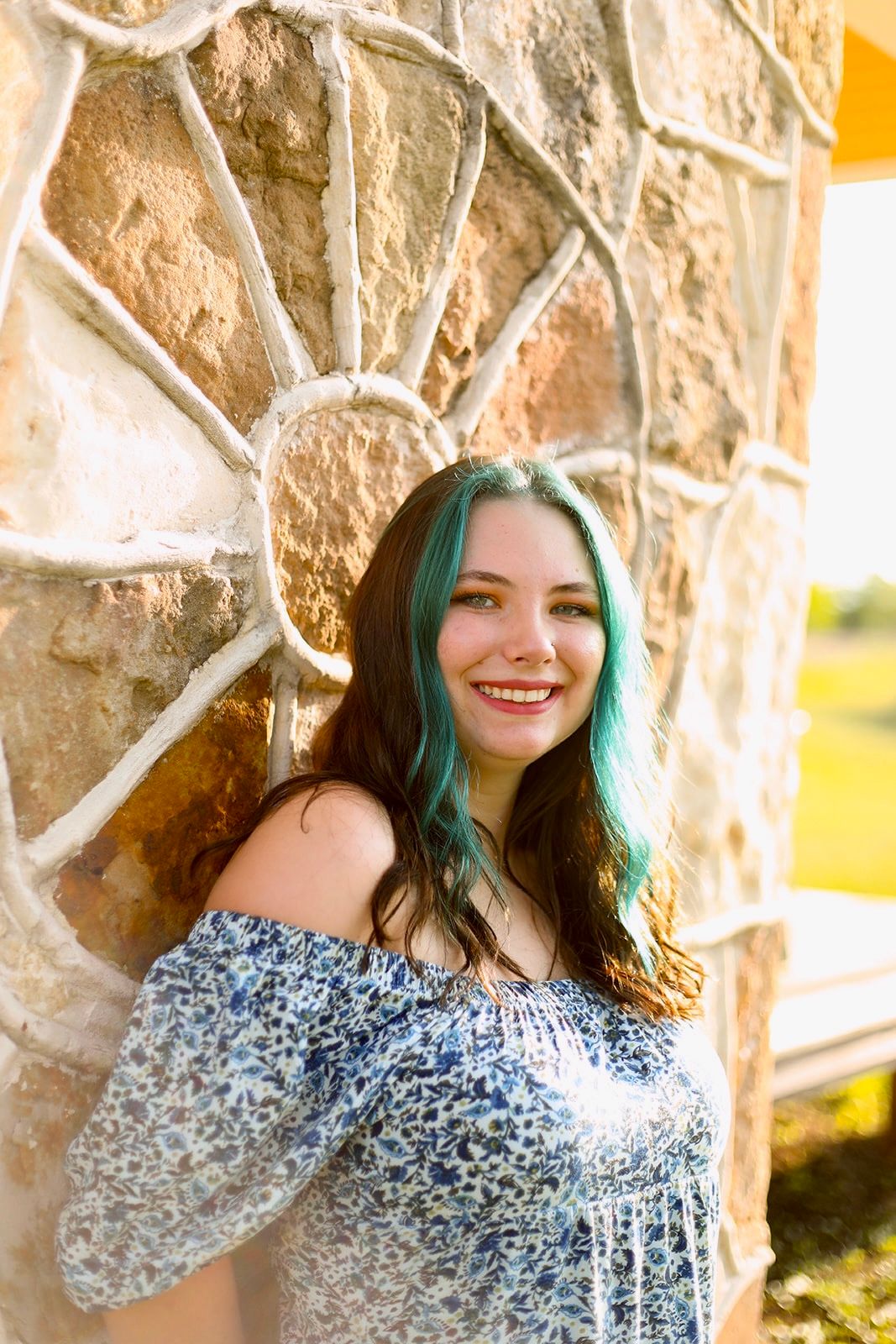 Portrait session against textured stone wall with warm evening lighting.