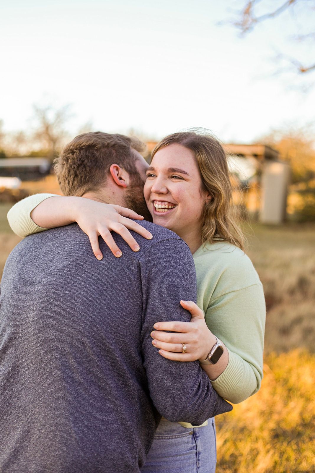 Couple shares joyful embrace in golden autumn field.