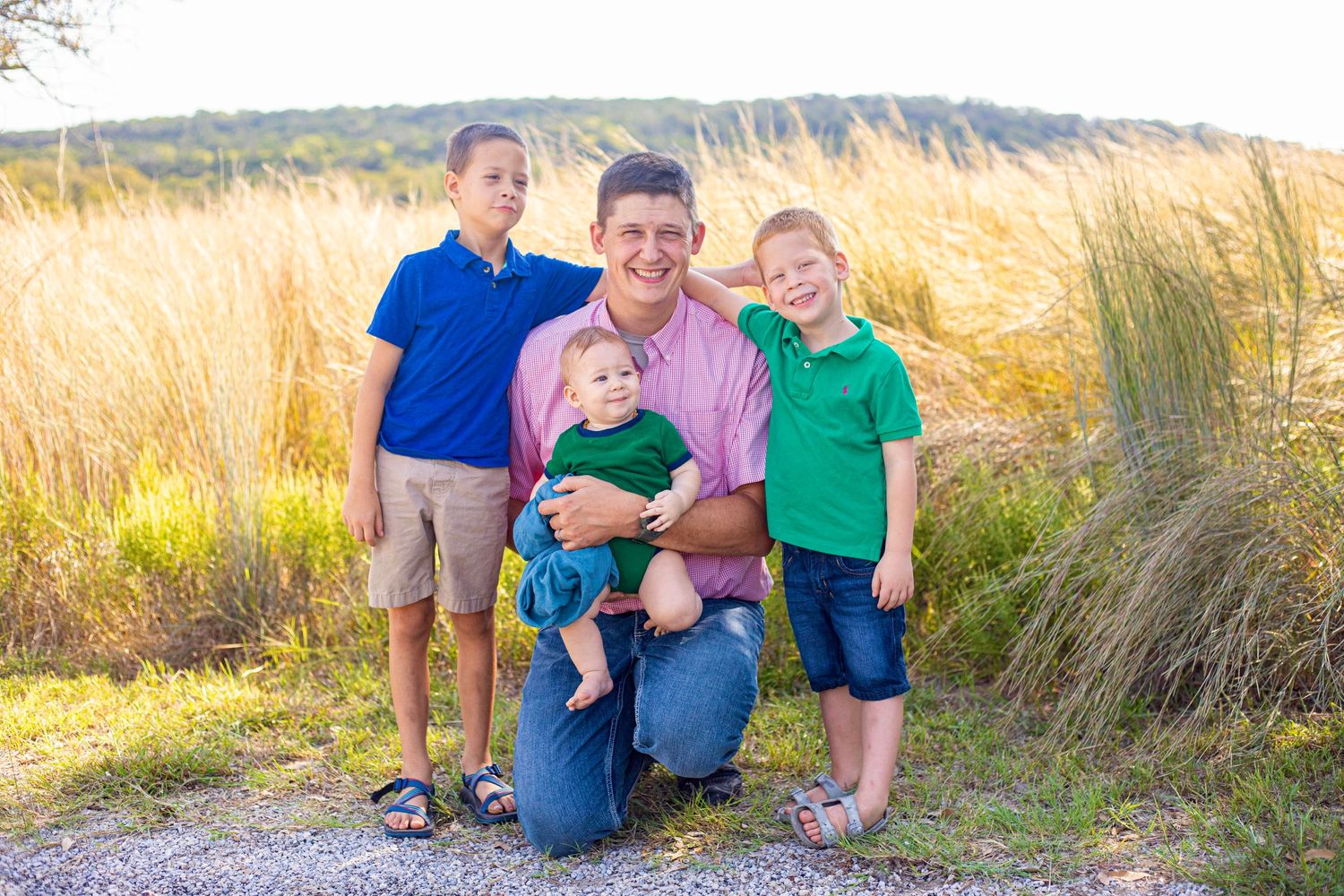 Family group photo session in a scenic field during golden hour.