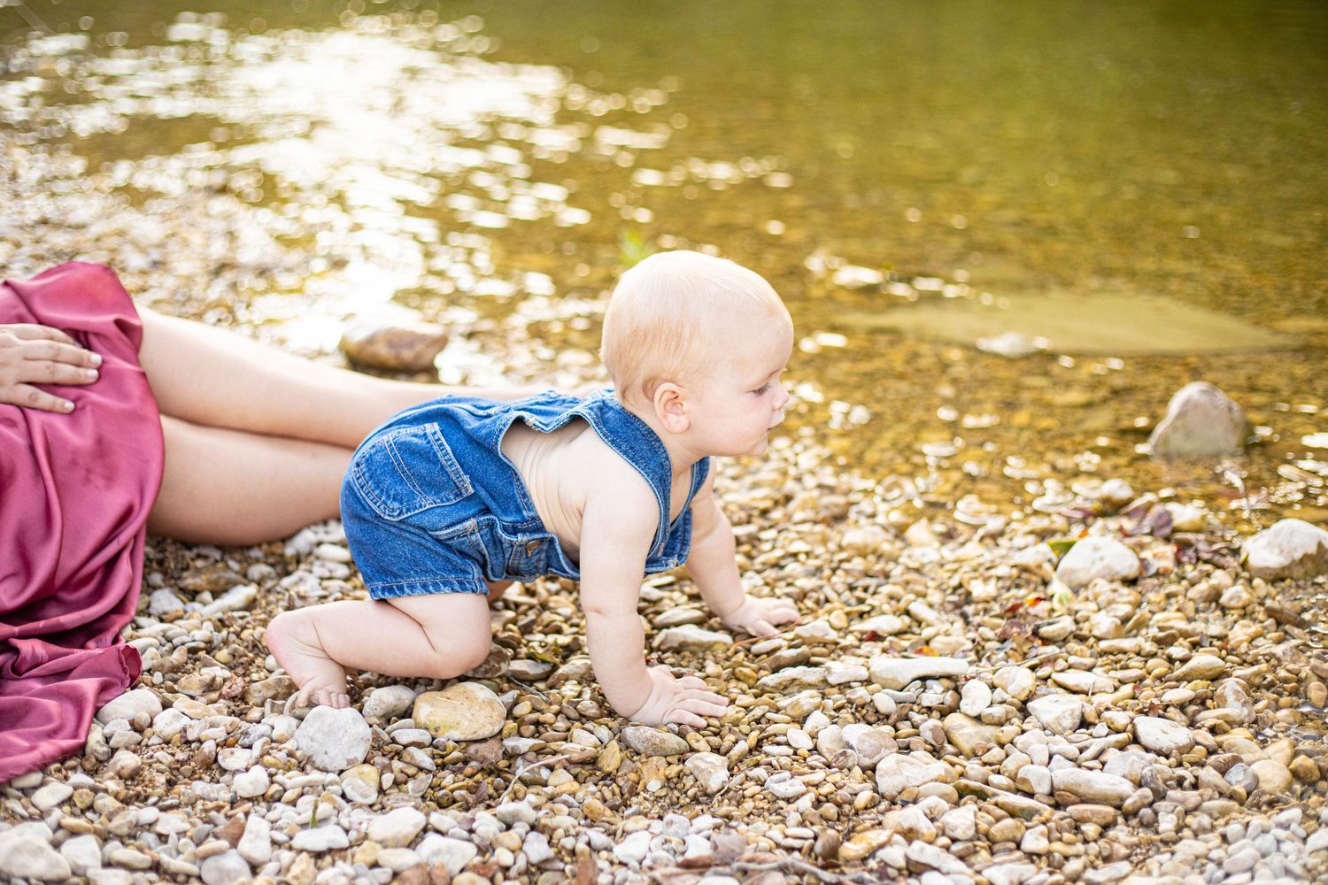 Rocky riverbank scene with sunlit water and pebbles.