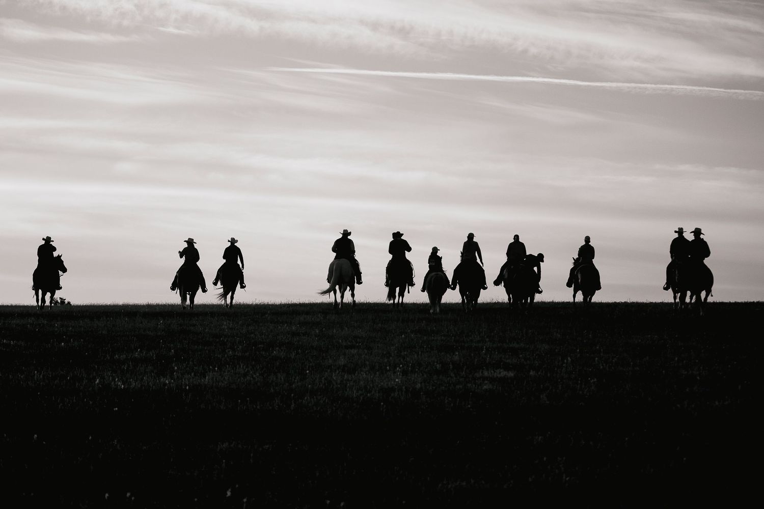 11 cowboys riding off in the sunrise to gather cattle for the spring branding