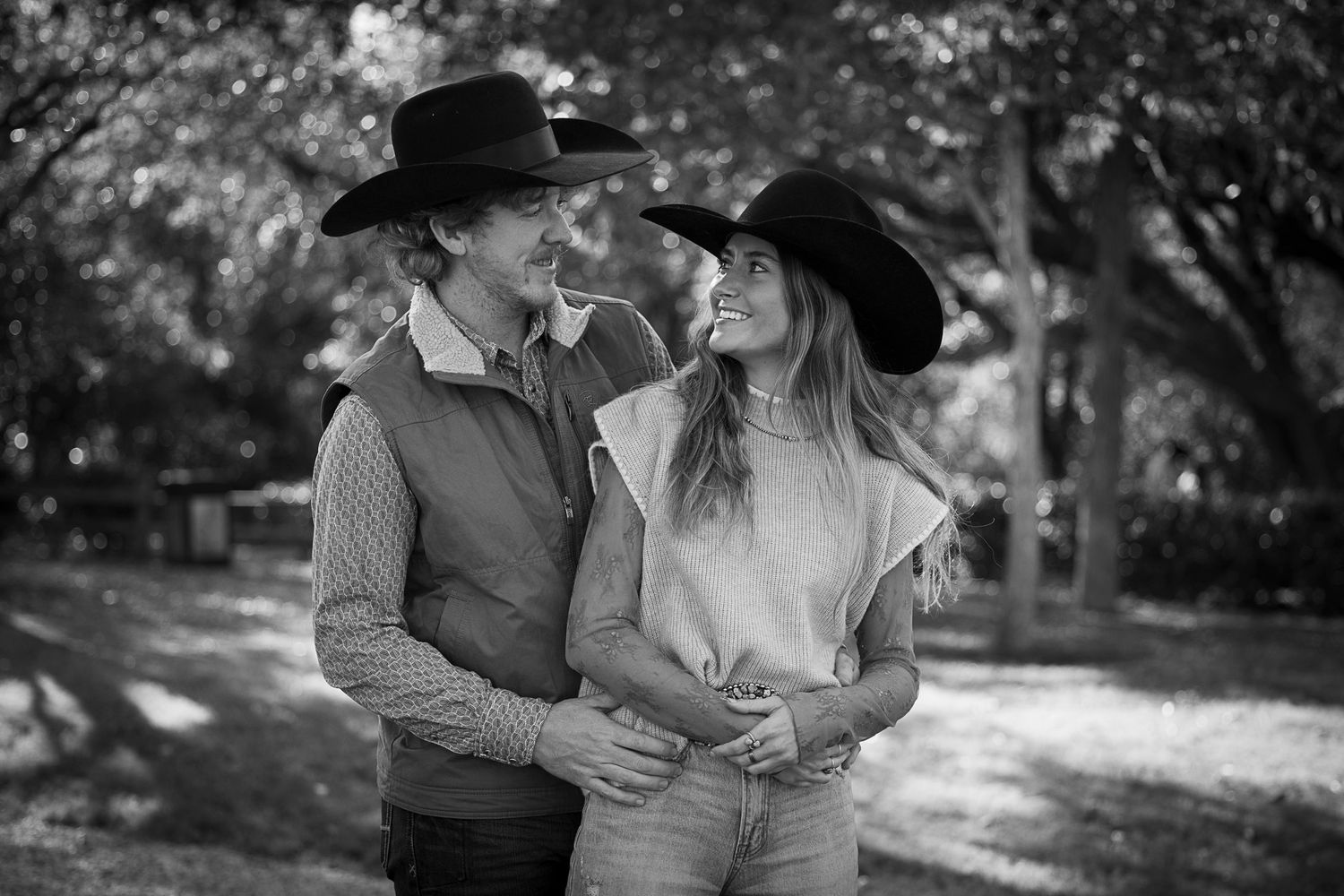 A romantic black and white portrait of a western couple in cowboy hats sharing an intimate at the Carleen Bright Arboretum in Woodwa, Texas.