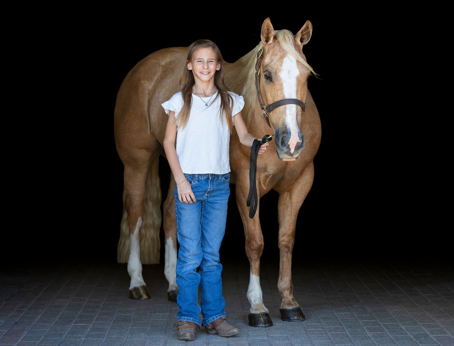 Black background portrait of a girl and her palomino horse
