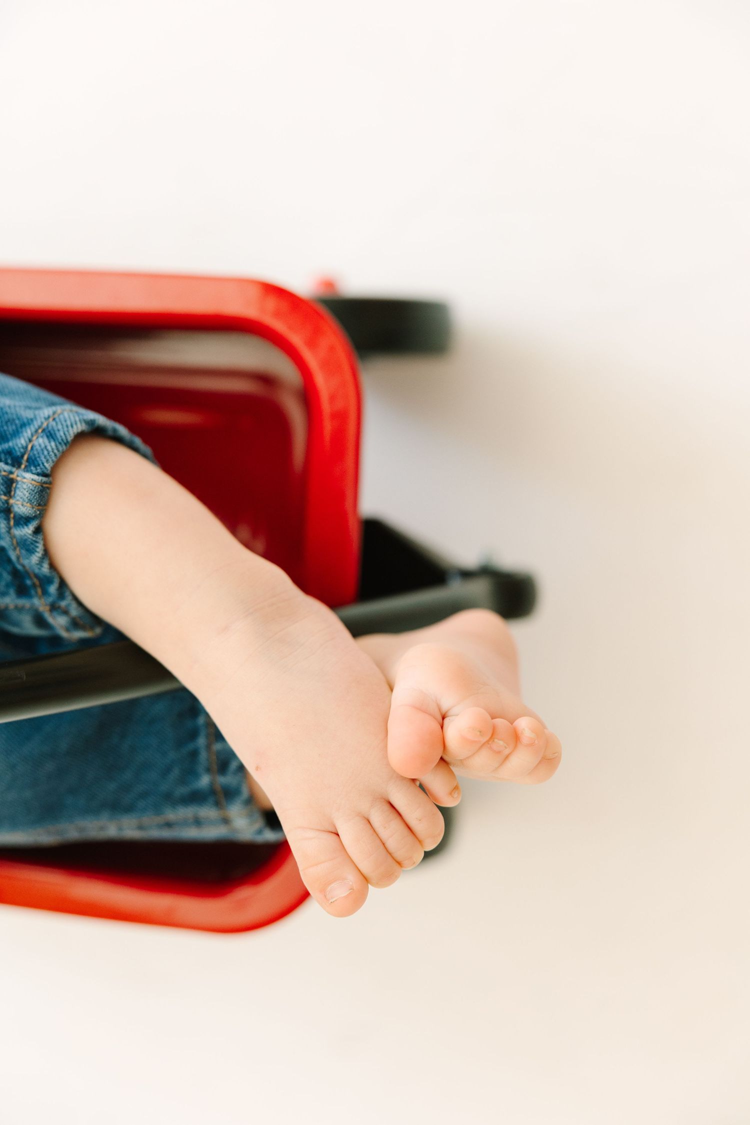 Close-up view of tiny baby feet resting on a red surface.